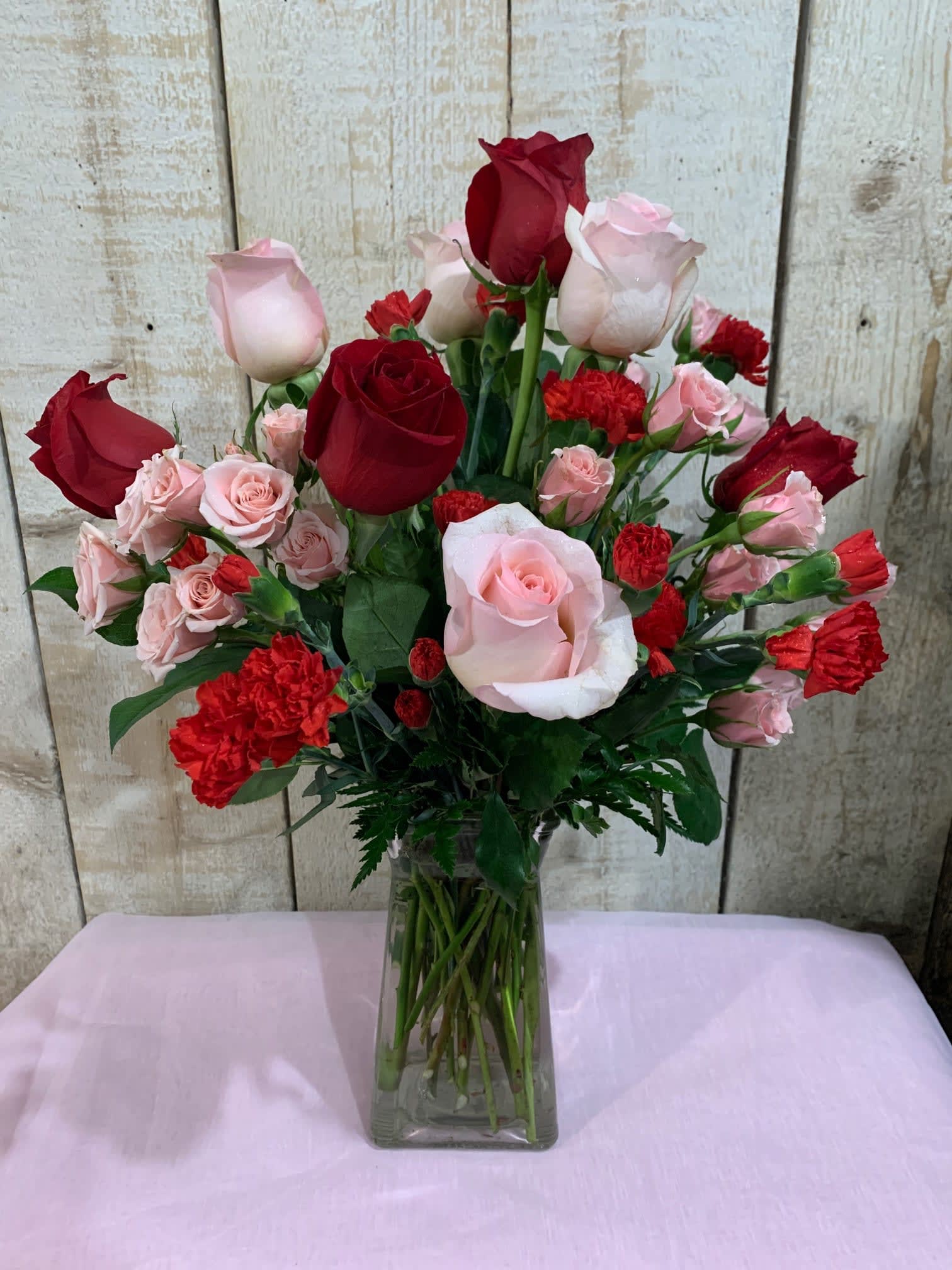 Bouquet of red and pink roses with carnations in a glass vase