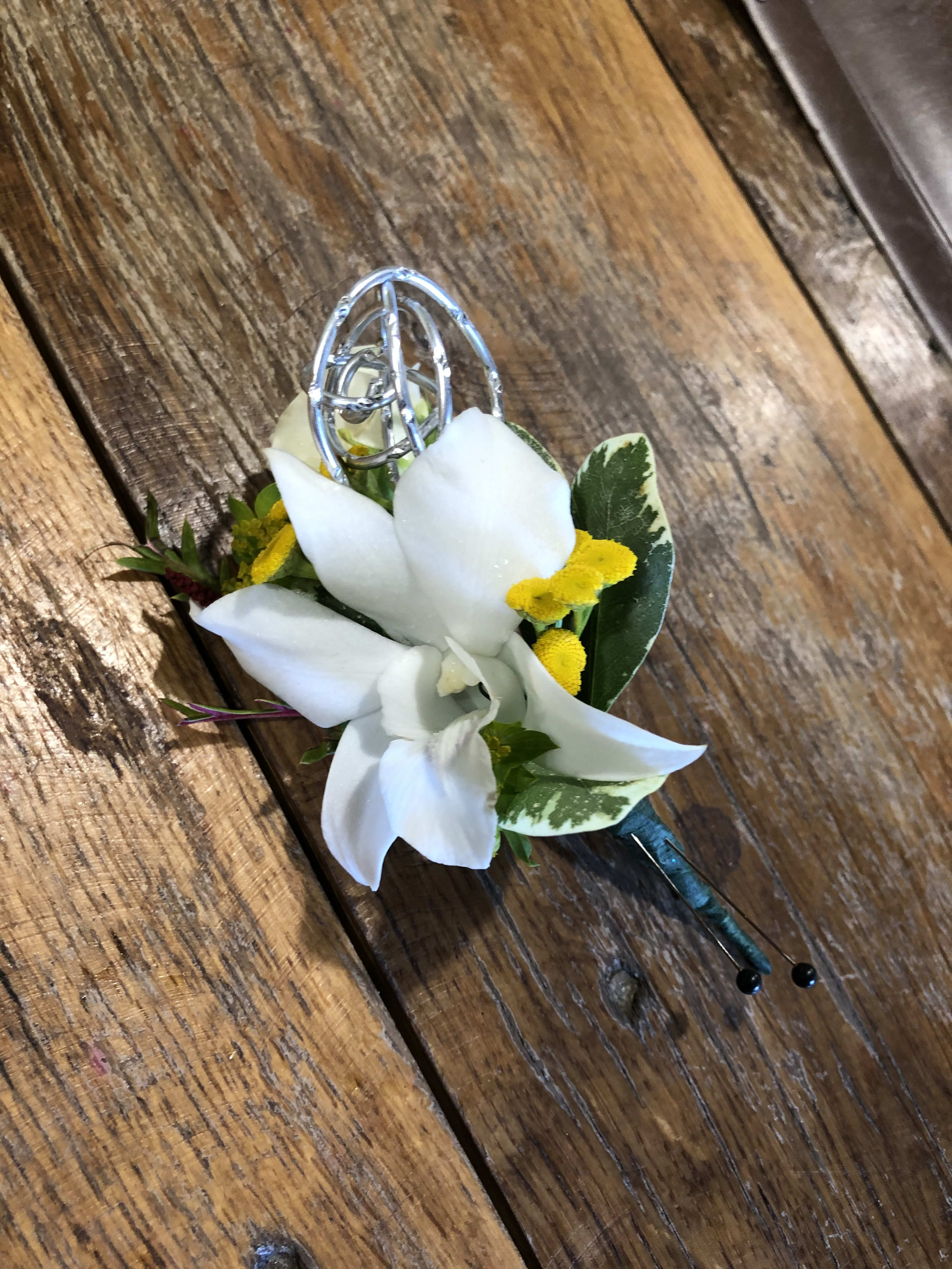 White orchid boutonniere with yellow accents and a silver pin