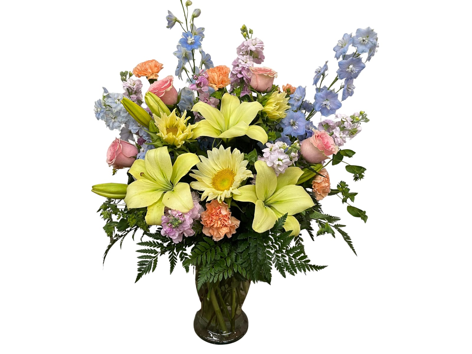 Mixed bouquet of lilies, roses, and blue flowers in a glass vase