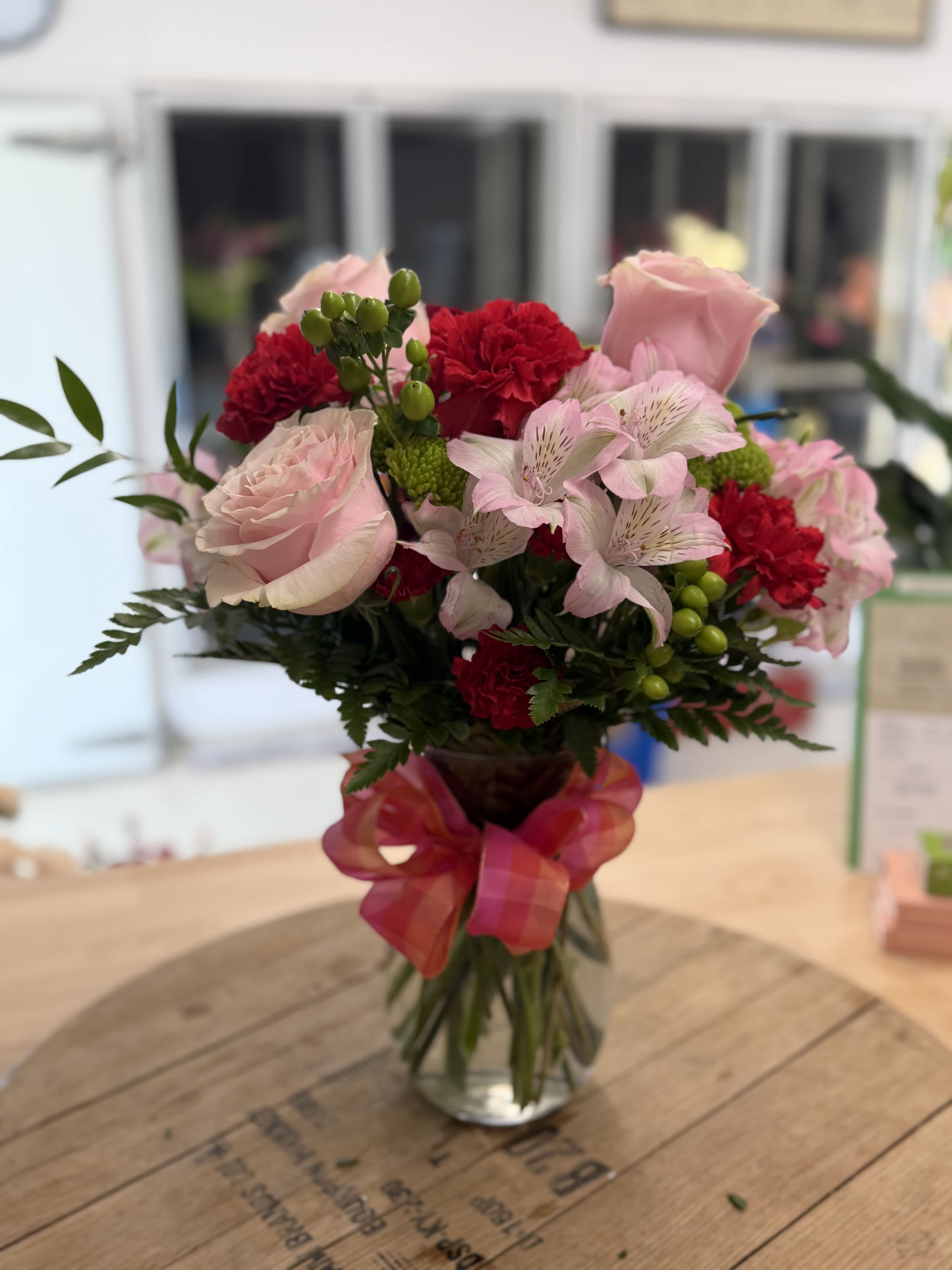 Pink and red mixed bouquet in a glass vase with a ribbon