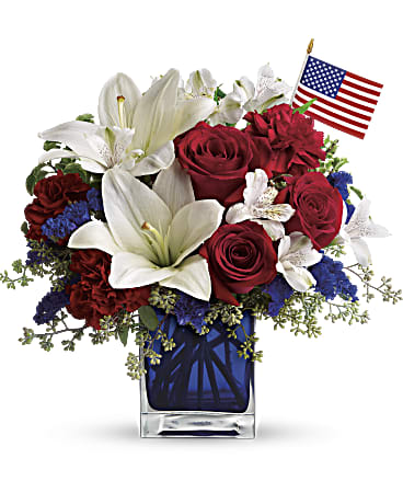 Red roses and white lilies in a blue vase with a small American flag
