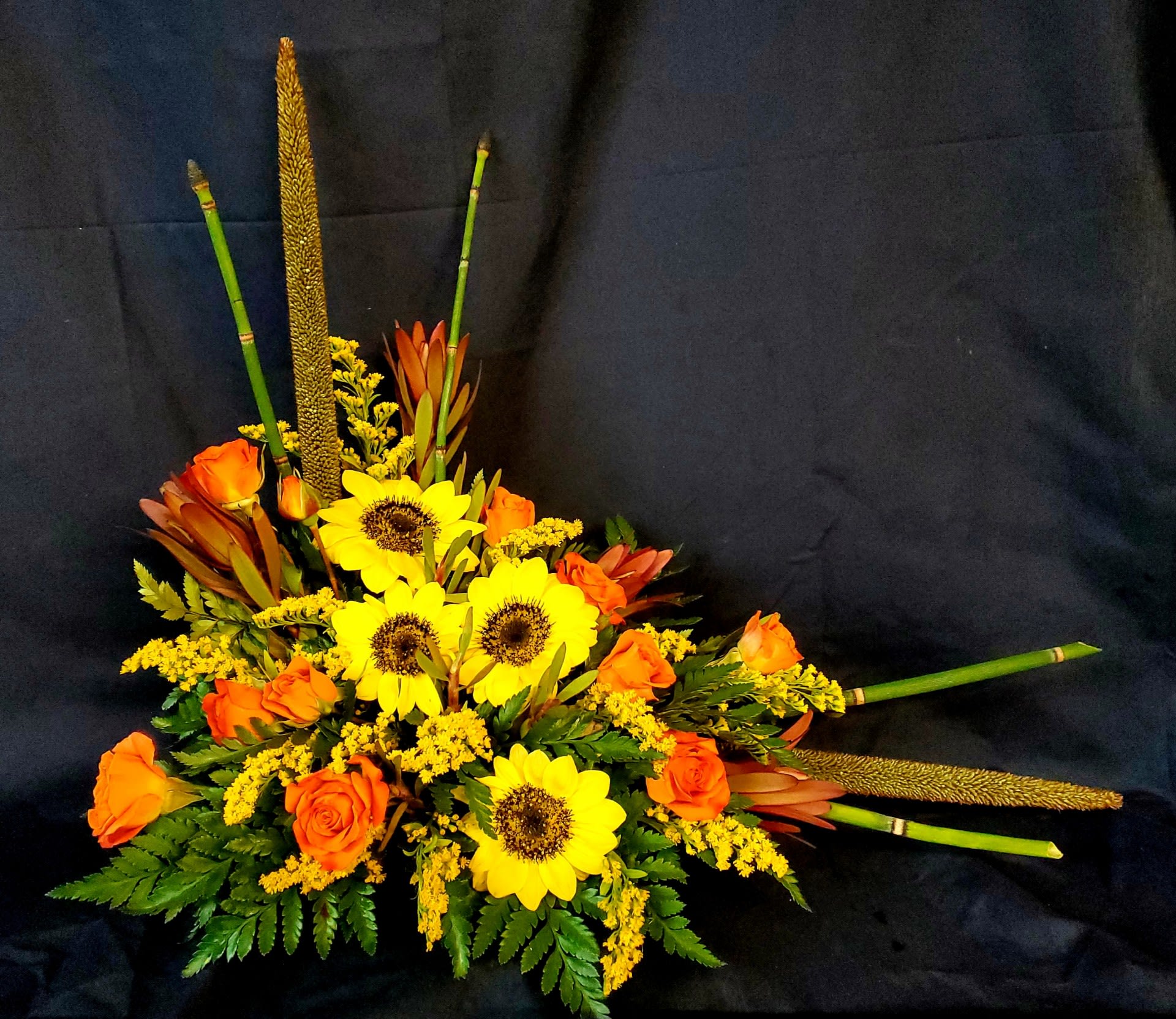 Orange roses and yellow sunflowers in a low floral arrangement