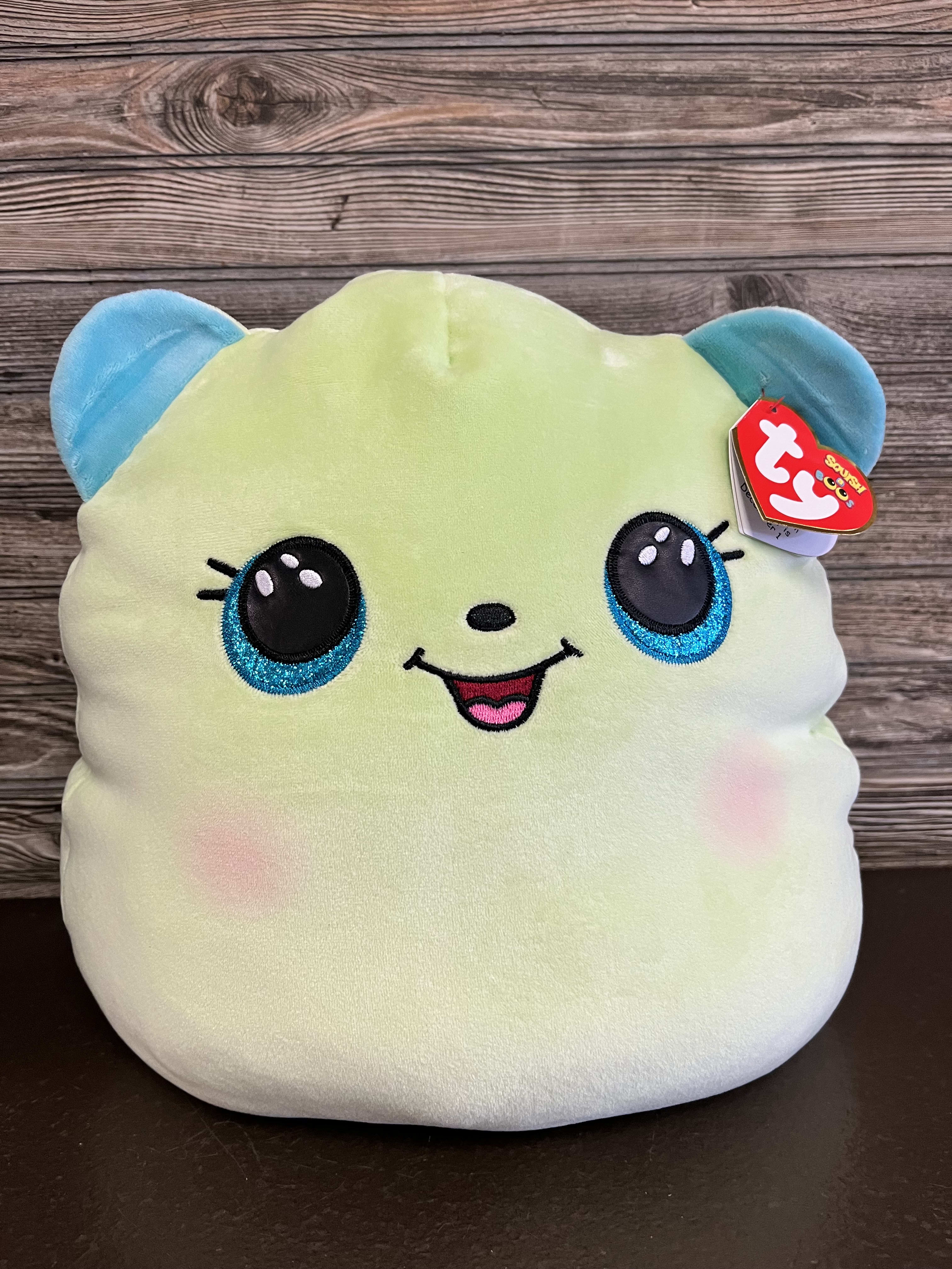 Plush toy with a smiling face and blue ears on a wooden background