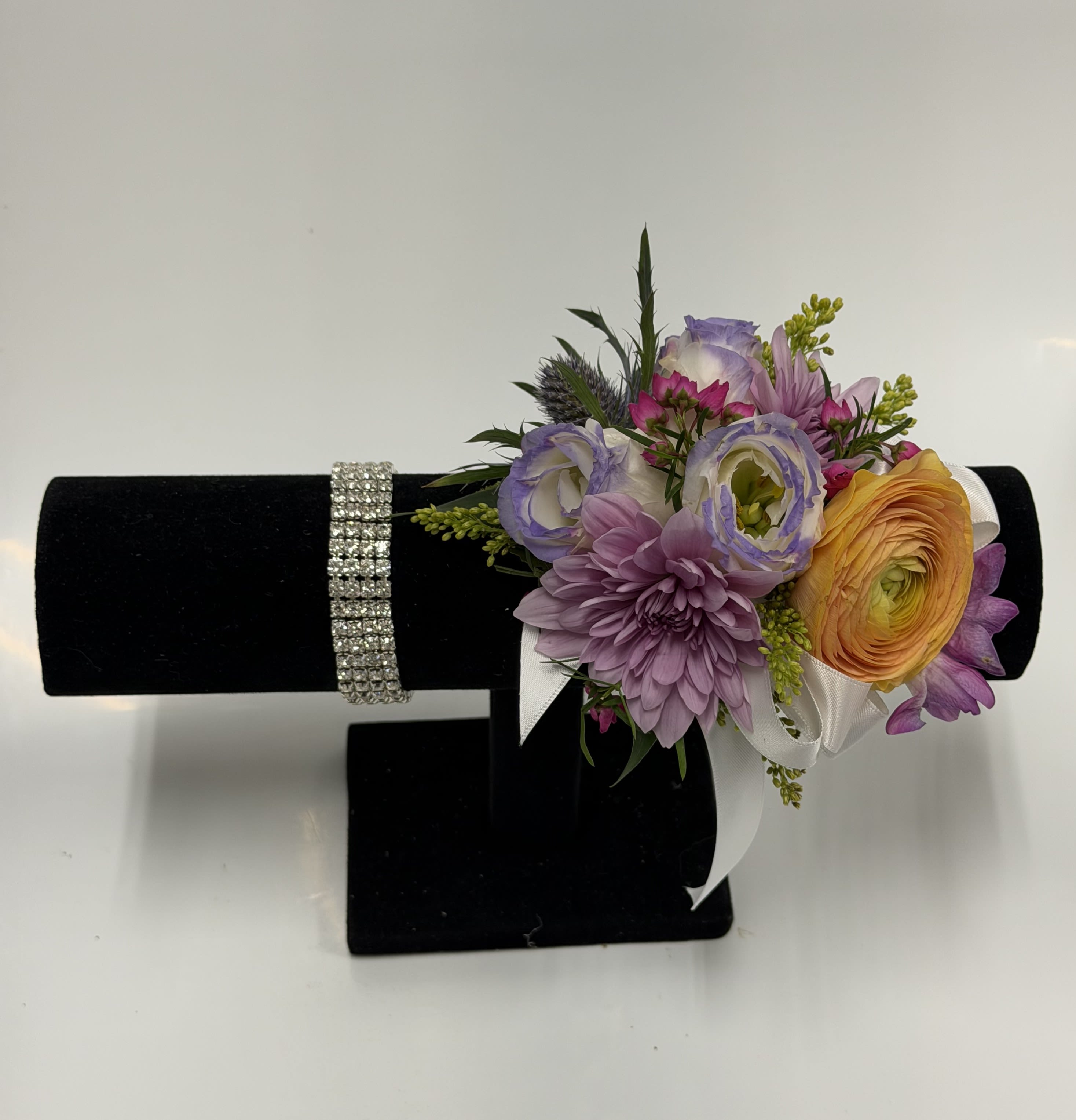  COLORFUL ENGLISH GARDEN CORSAGE WITH SILVER RHINESTONE WRISTLET - Ranunculus, lisianthus, and a variety of other flowers in soft spring colors, accented with filler and greenery on a silver rhinestone band. Ribbon color can be customized; please specify in the pick-up note section. ***Will NOT be identical to photo***