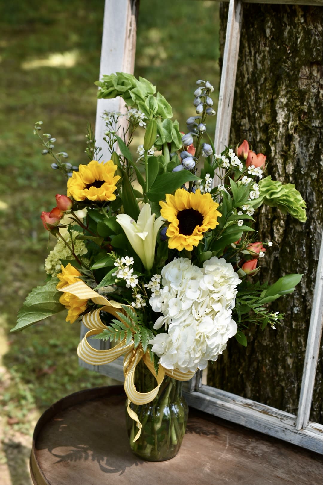 Bouquet of sunflowers, white lilies, and white hydrangea in a glass vase