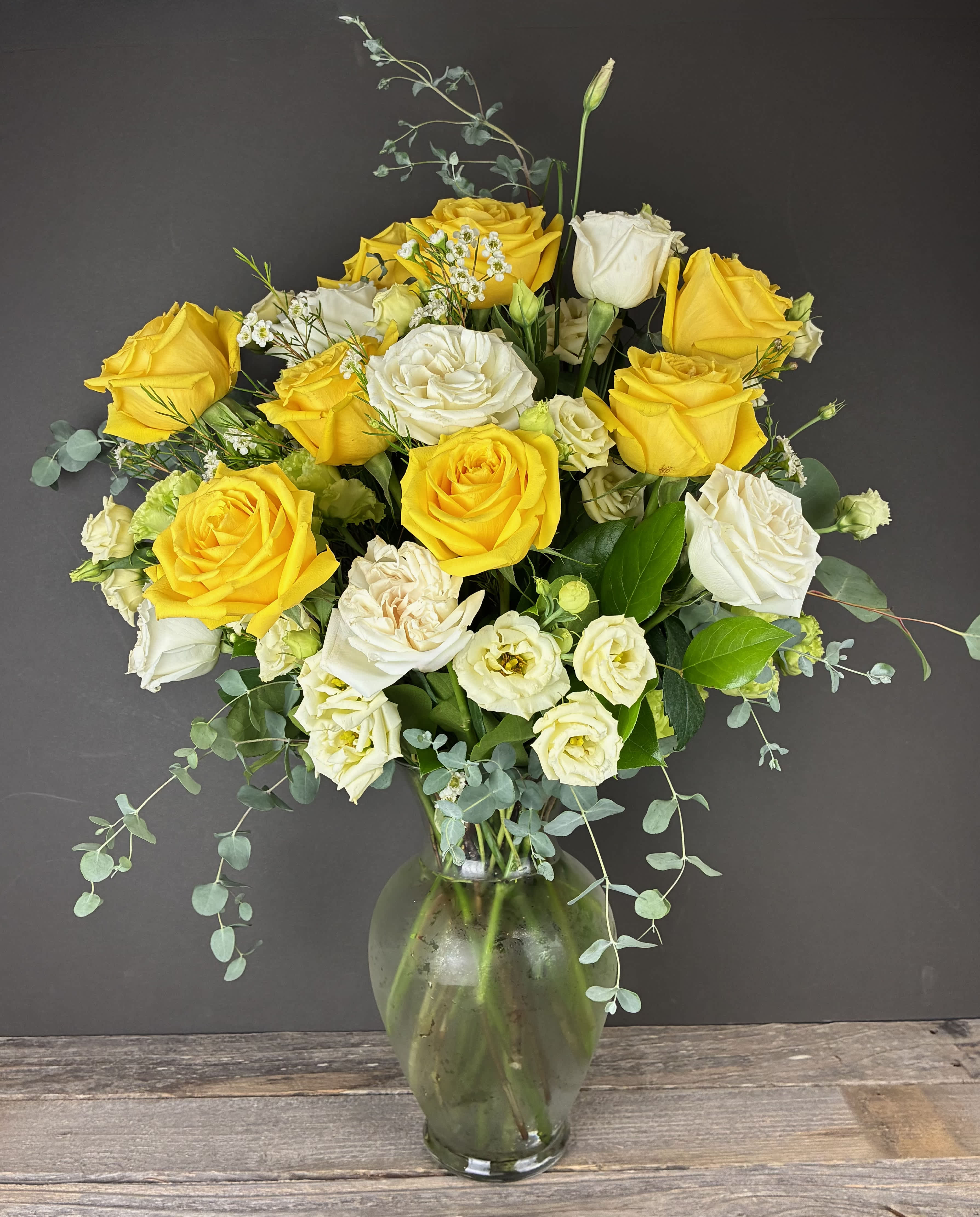 Yellow and white roses arranged in a clear glass vase