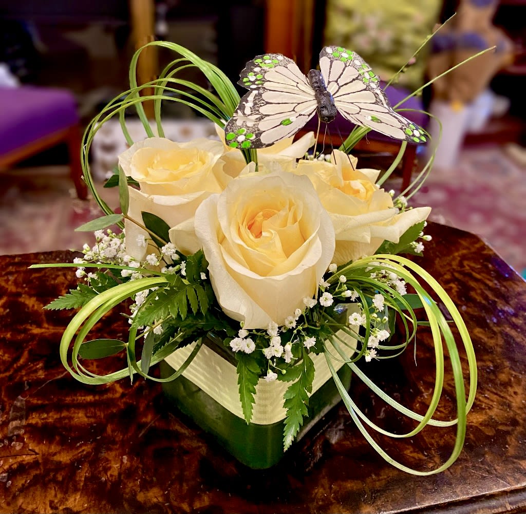 Cream roses in a square vase with a butterfly decoration