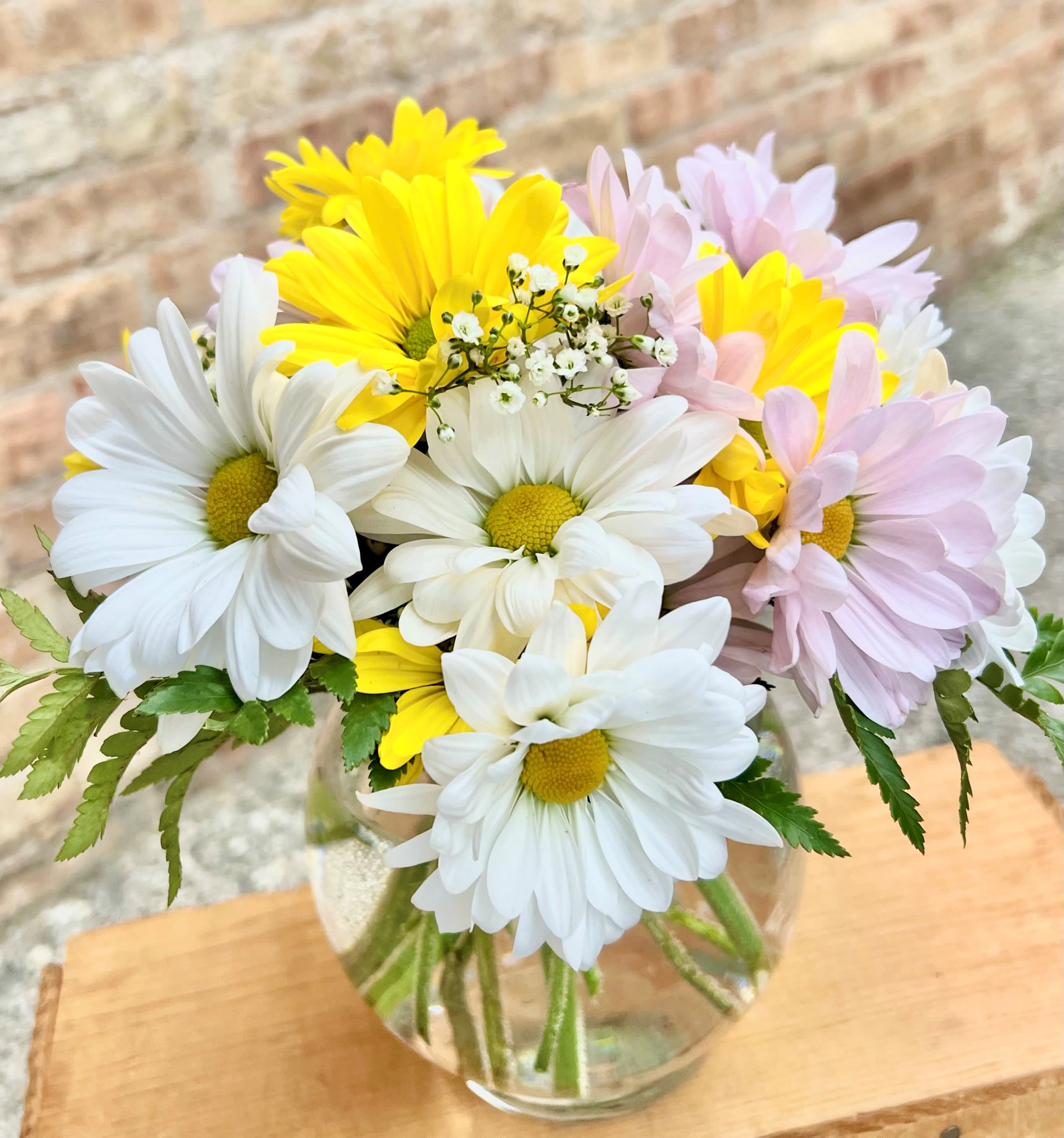 Bouquet of white, yellow, and pale pink daisies in a glass vase