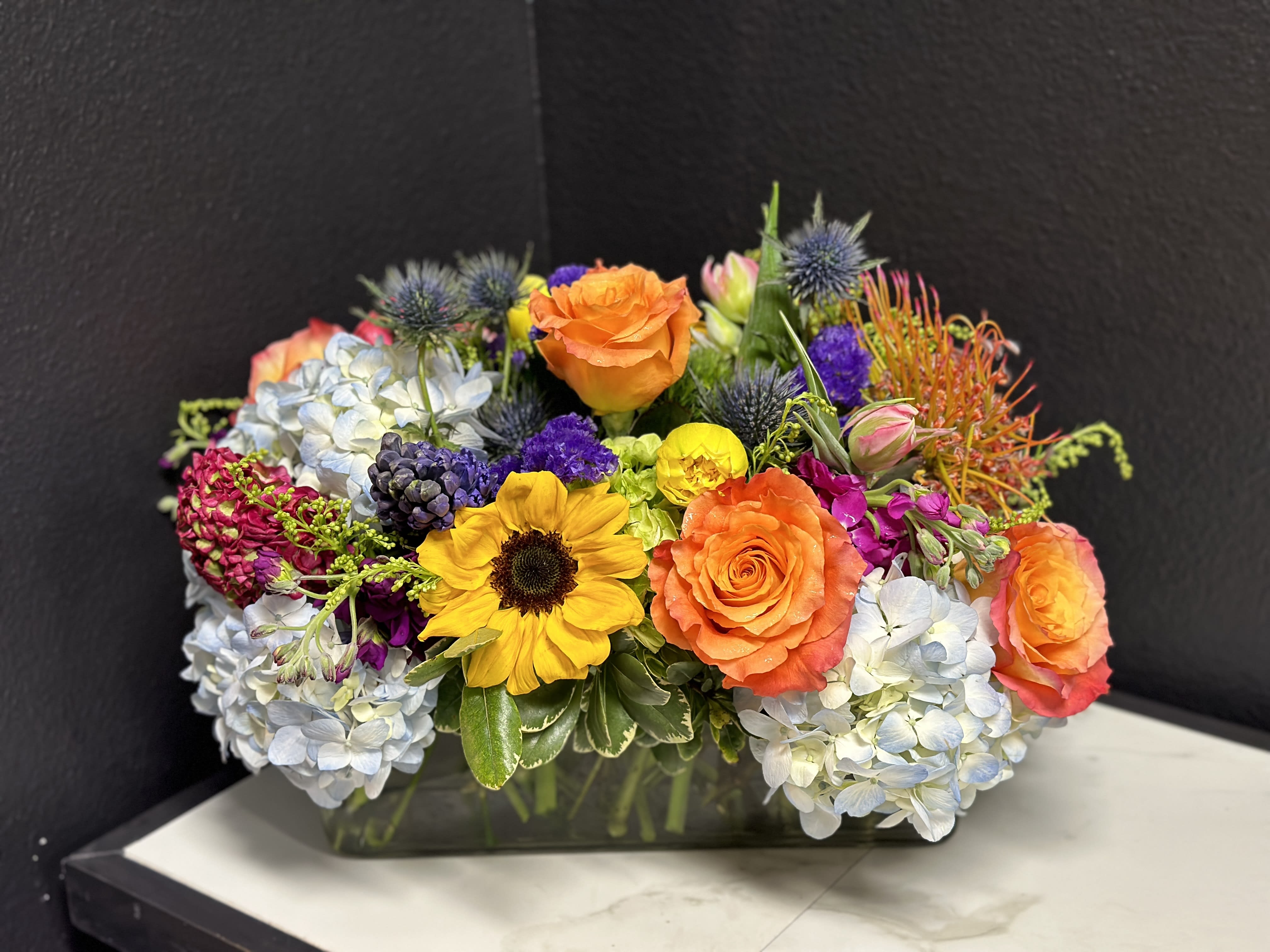 Colorful mixed flower arrangement in a rectangular glass vase