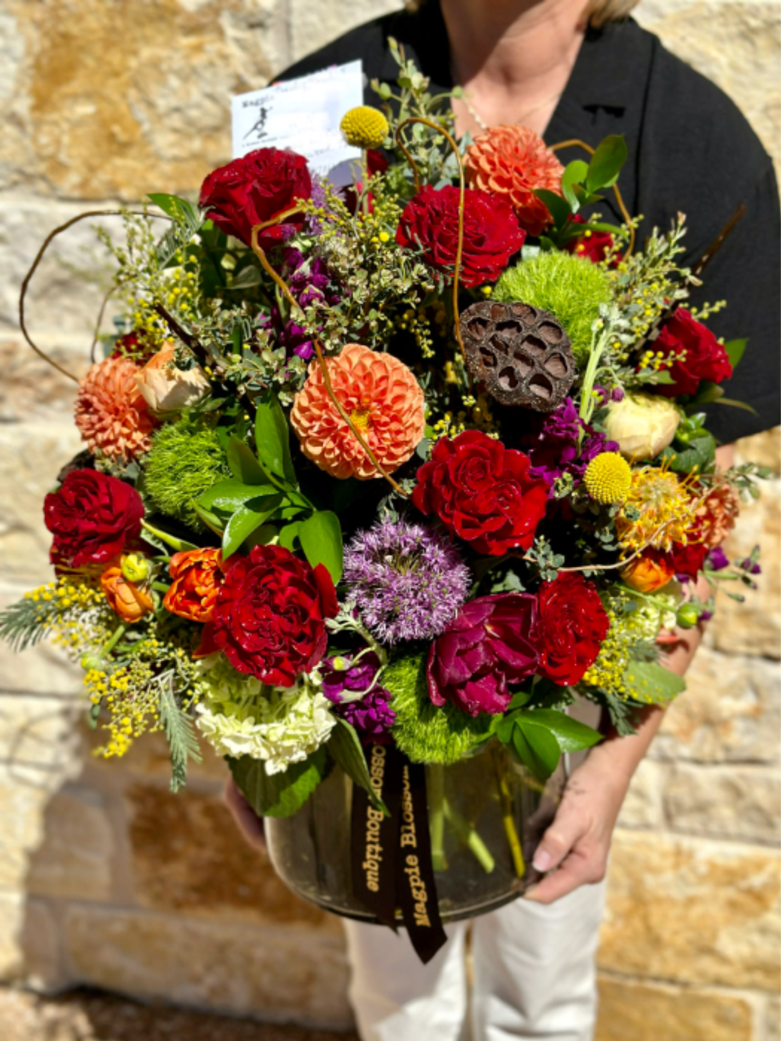 Large mixed bouquet in a glass vase with red, orange, and purple blooms