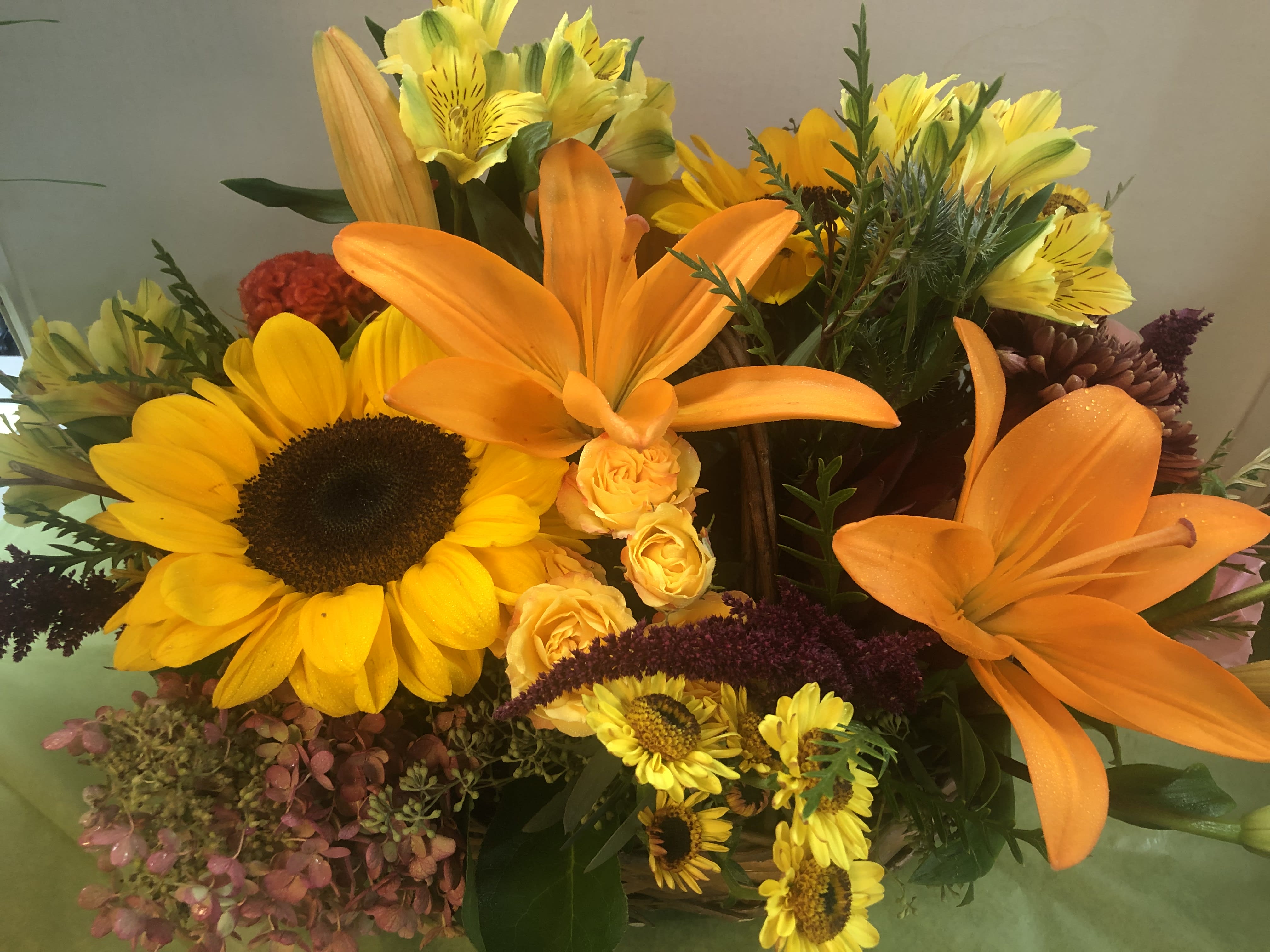 Cheery  Seasonal Arrangement - Sunflower, Lilies, Seasonal Flowers, Fancy green.  Note:   There are a variety of Sunflowers.  We cannot guarantee  which variety will be available.
