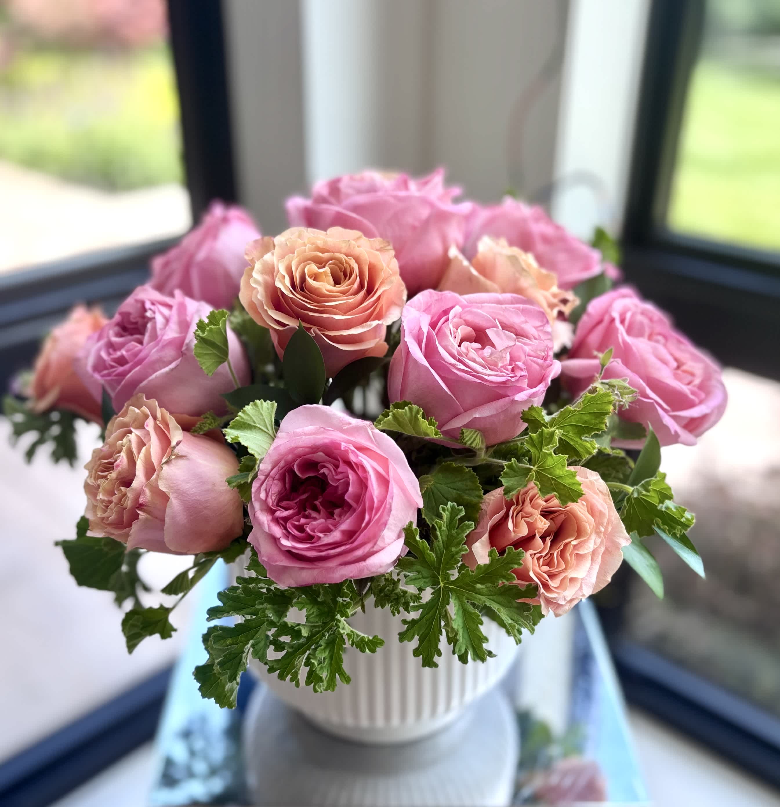 Pink and peach roses arranged in a white vase