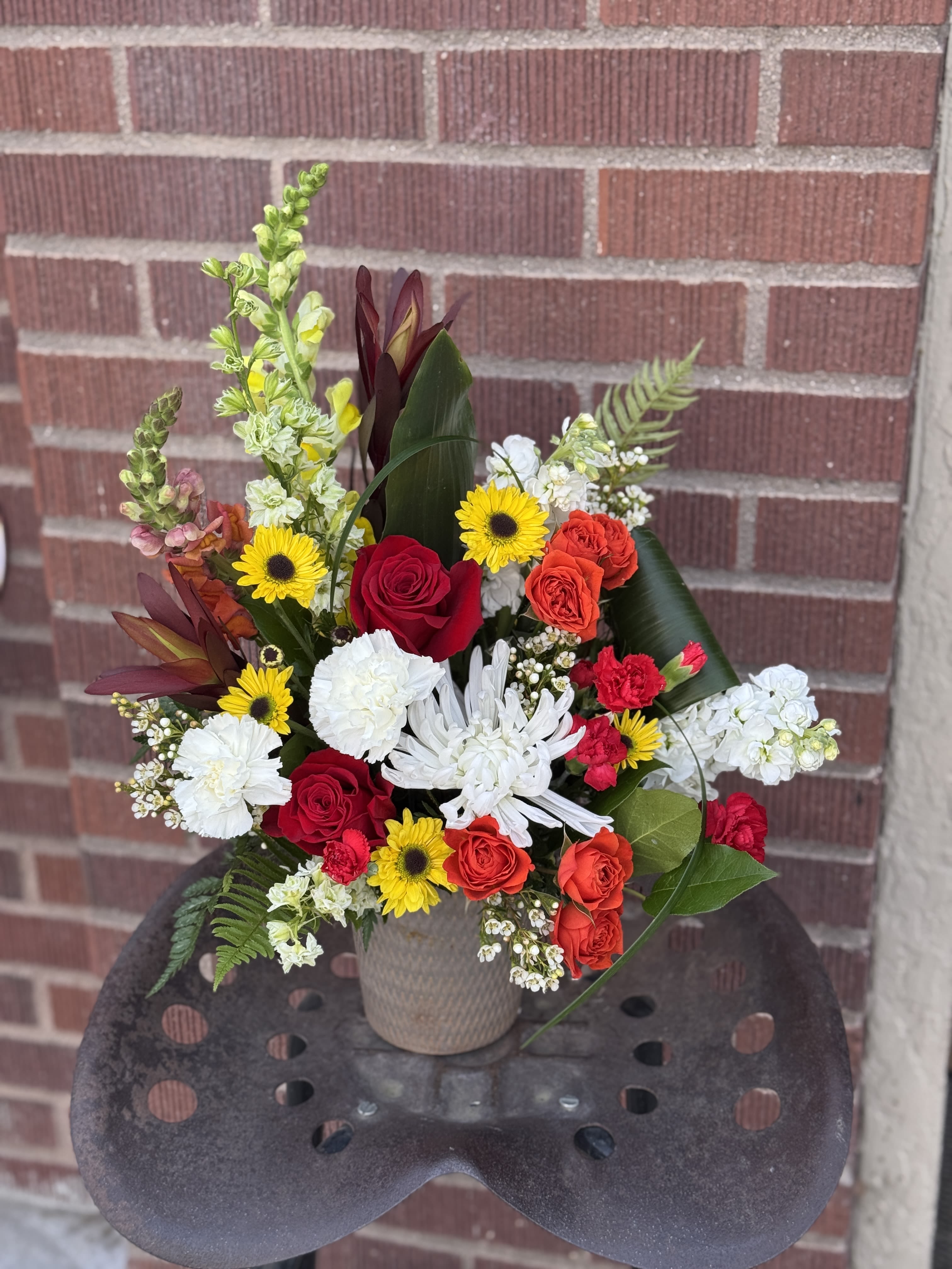 Mixed bouquet in a beige vase with red, white, and yellow flowers