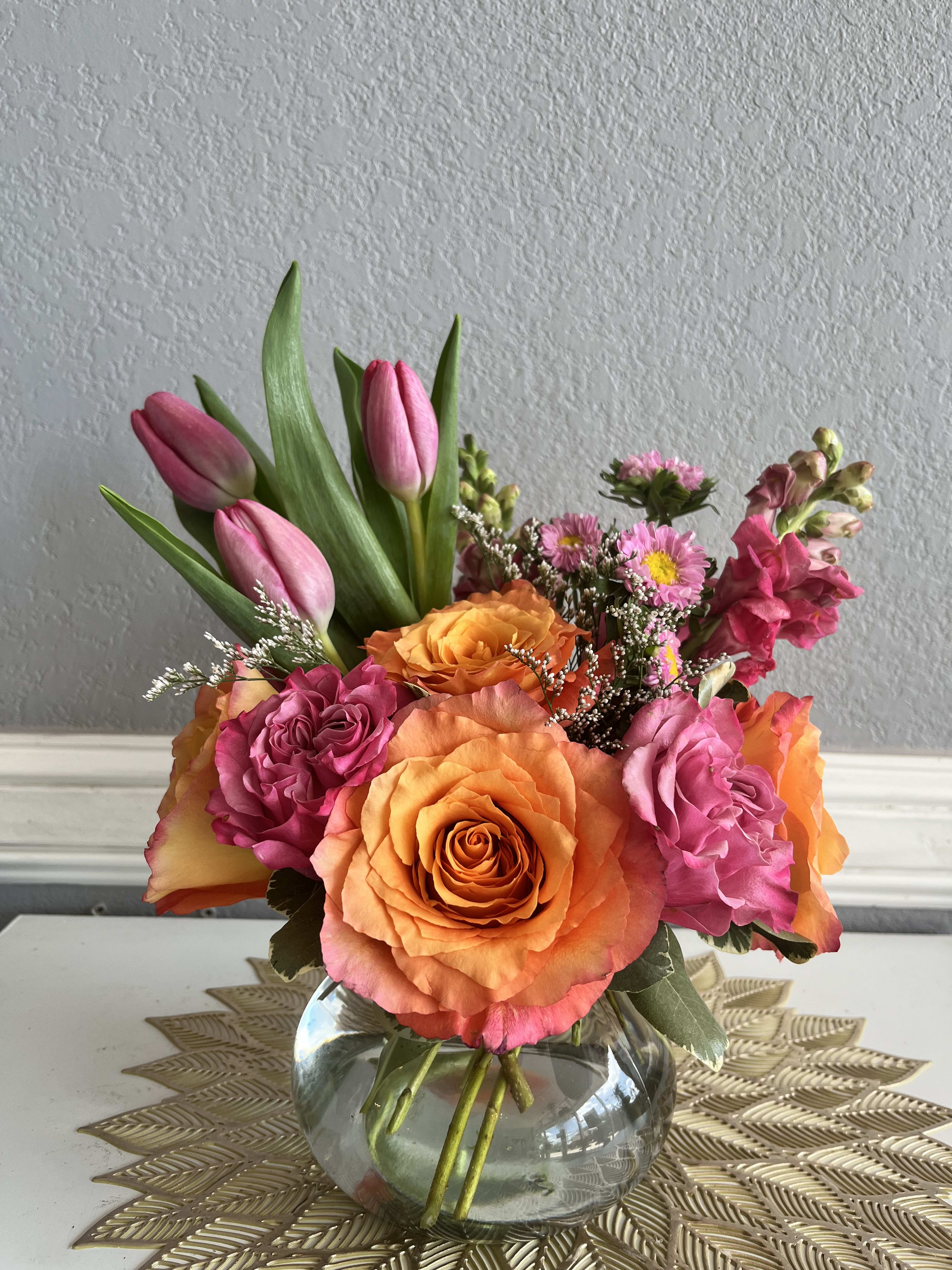 Pink tulips and orange roses arranged in a glass vase