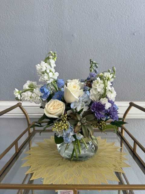 Mixed bouquet of white, blue, and purple flowers in a glass vase
