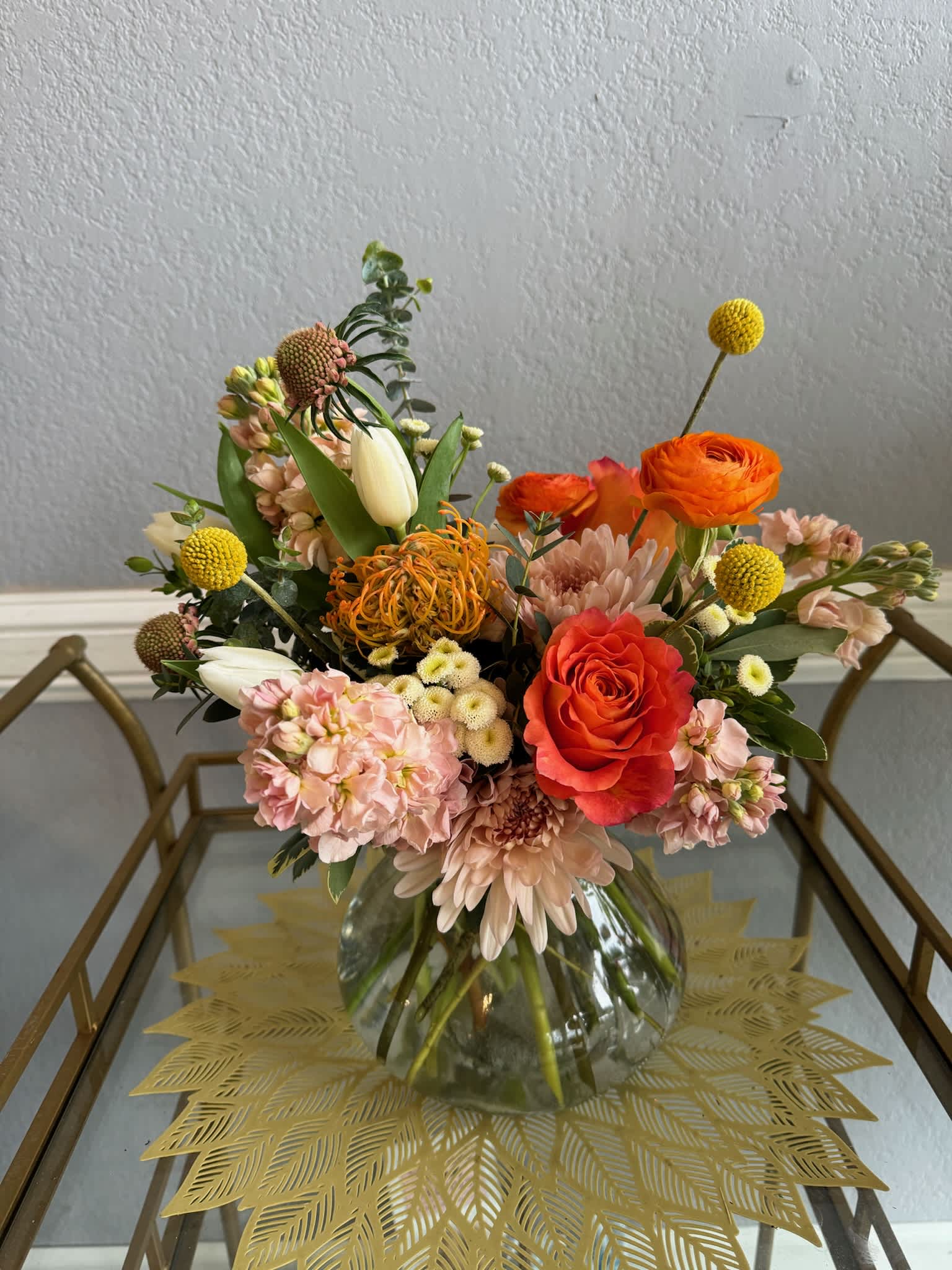 Mixed bouquet in a clear glass vase with orange and blush flowers