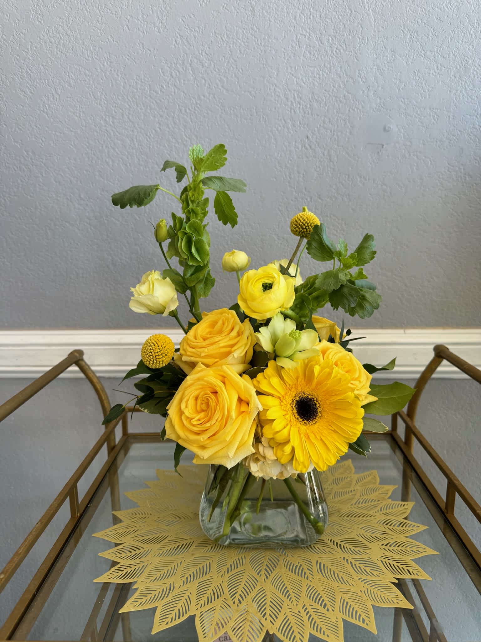 Yellow roses and a gerbera daisy in a glass vase