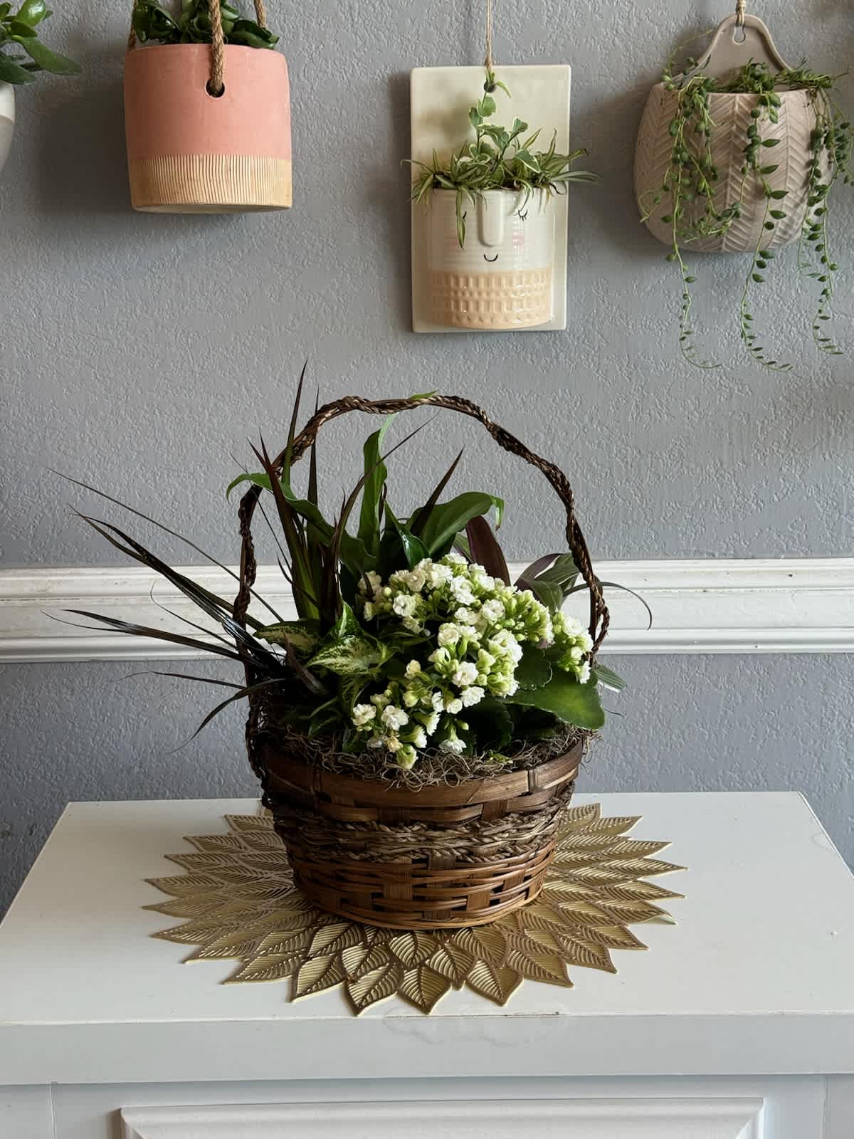 Basket arrangement with white flowers and mixed green plants