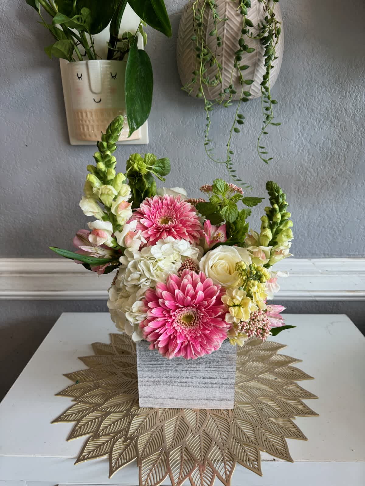 Pink and white flowers arranged in a square gray vase