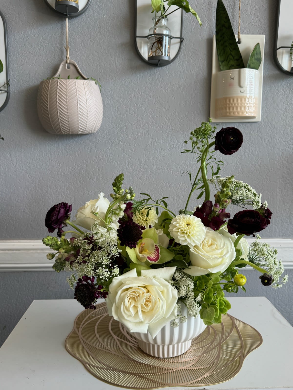 White and dark burgundy floral arrangement in a ribbed white vase