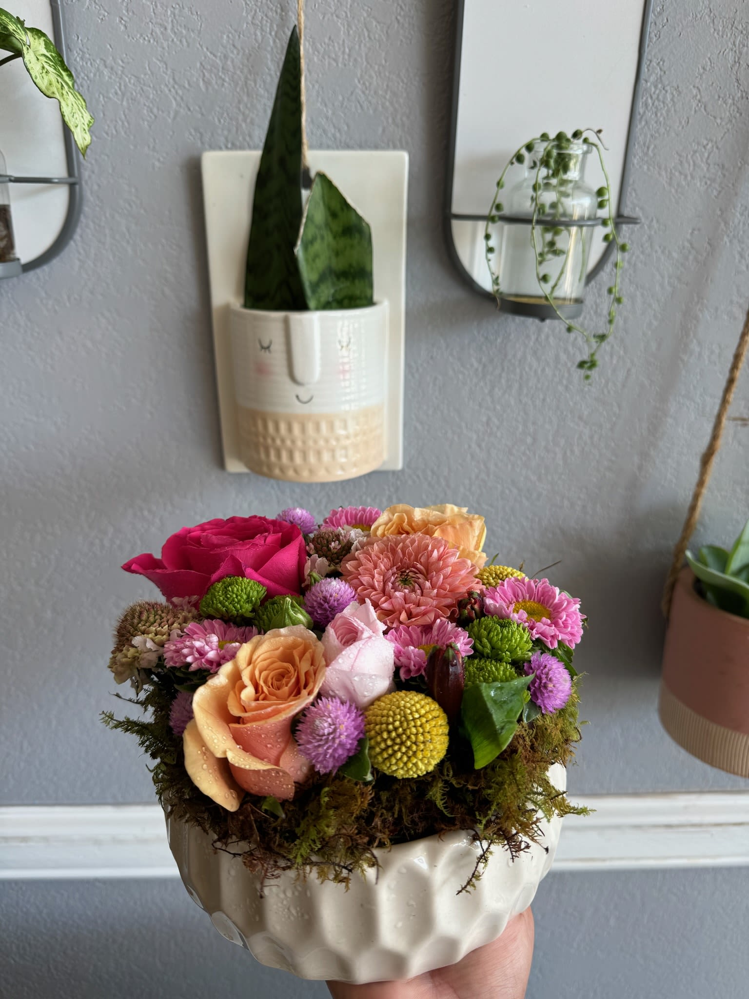 Compact bouquet of pink, peach, and yellow flowers in a white ceramic bowl