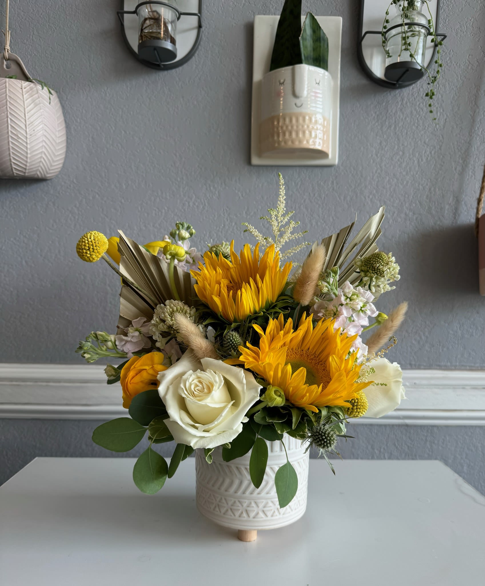 Yellow and white floral arrangement in a white ceramic pot
