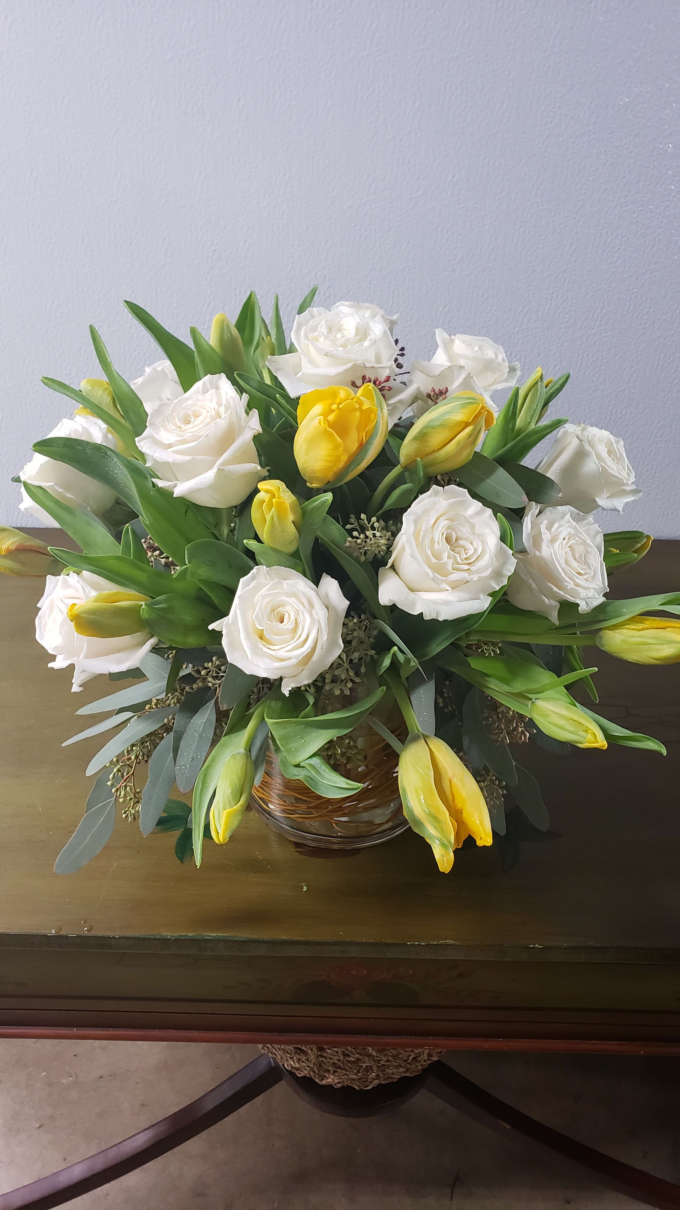 White roses and yellow tulips arranged in a glass bowl