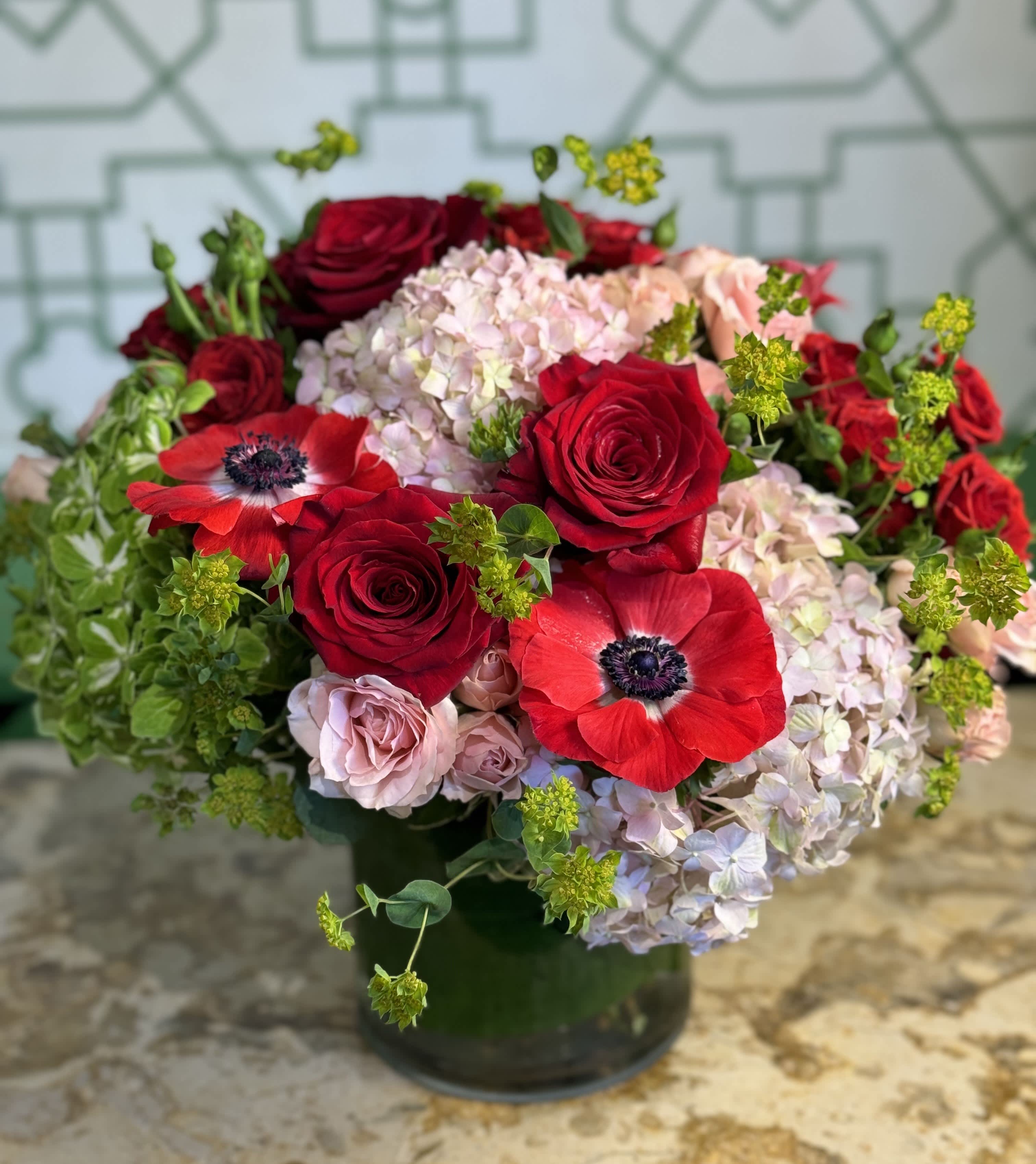 Red roses and pale hydrangeas arranged in a dark vase