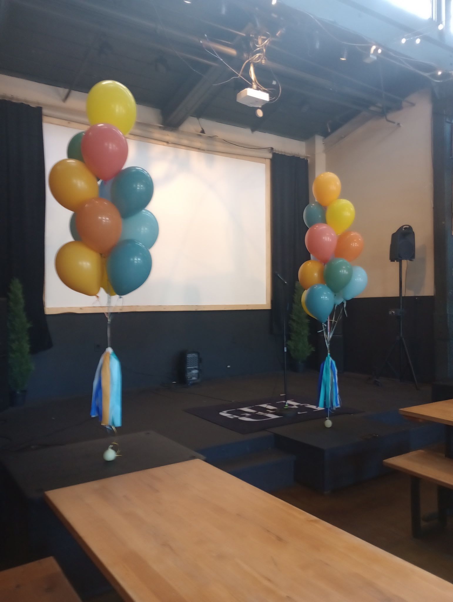 Clusters of colorful balloons on stands in an indoor event space
