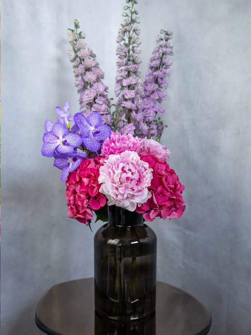 Pink and purple flowers arranged in a dark glass vase