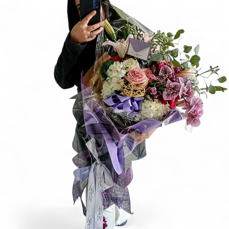 Purple Fashion Bouquet Designer's Choice - Roses orchids and so much more arranged as a presentation style bouquet wrapped in paper with long flowing ribbons. Perfect to hand to someone to show them how much you care. All of my bouquets are always made extra special and unique each and every time. Please check out my gallery to see my latest designs. Send them happiness. 
