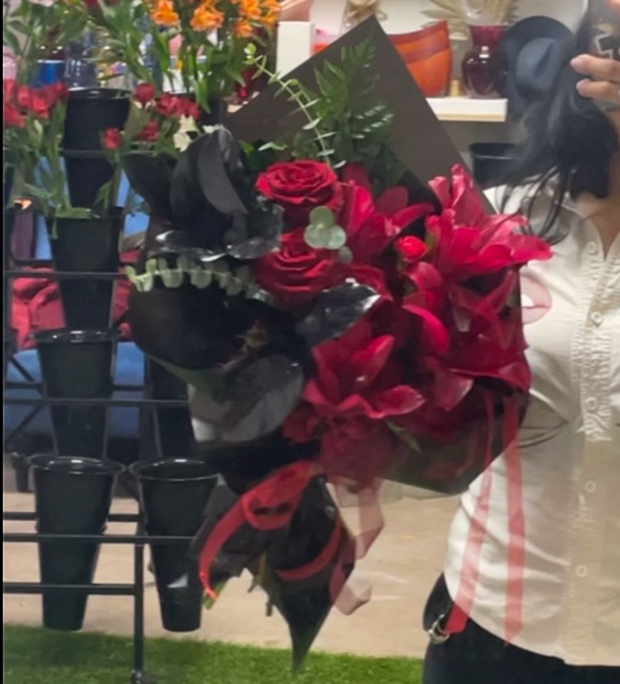 Bouquet of red roses and pink lilies wrapped in black paper