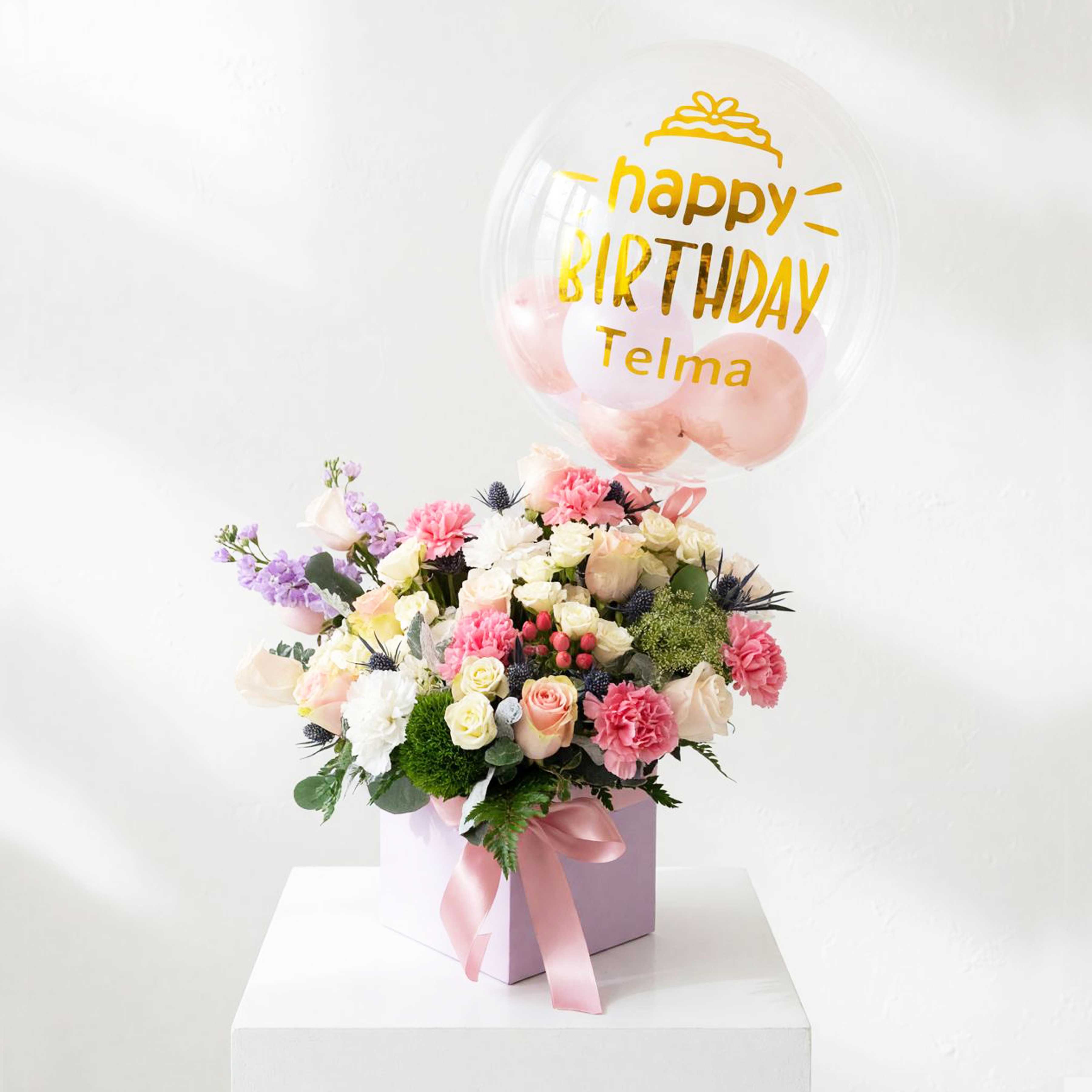 Pink and white flower arrangement with a birthday balloon in a gift box