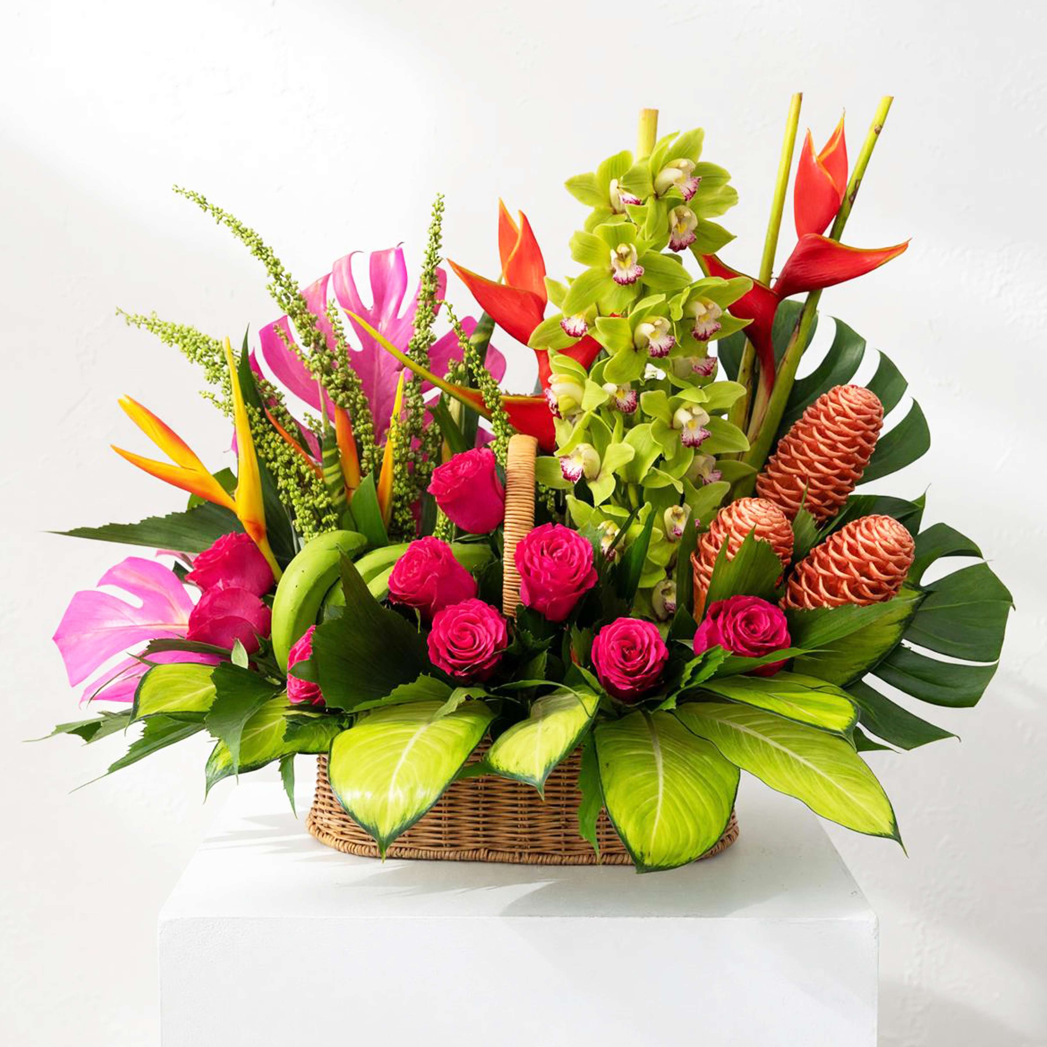Tropical flower arrangement in a wicker basket with pink roses and orchids