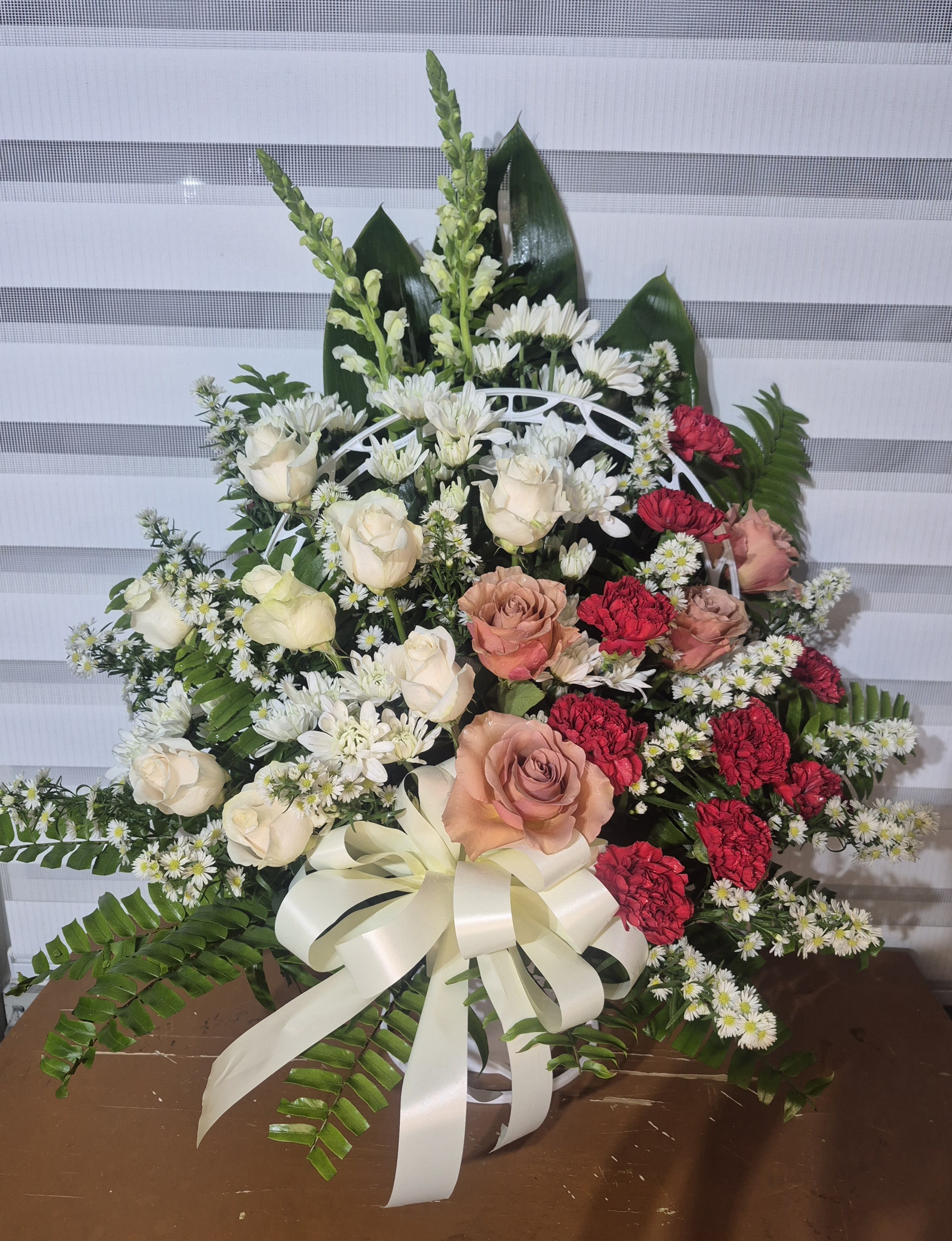 PEACEFUL WAY - 36 INCHES ONESIDED SYMPATHY ARRANGEMENT CONSISTING OF WHITE AND CORAL COLOR ROSES, WHITE MUMMS, WHITE SNAPDROGONS, RED CARNATIONS AND WHITE MONTICASINO FILLER.