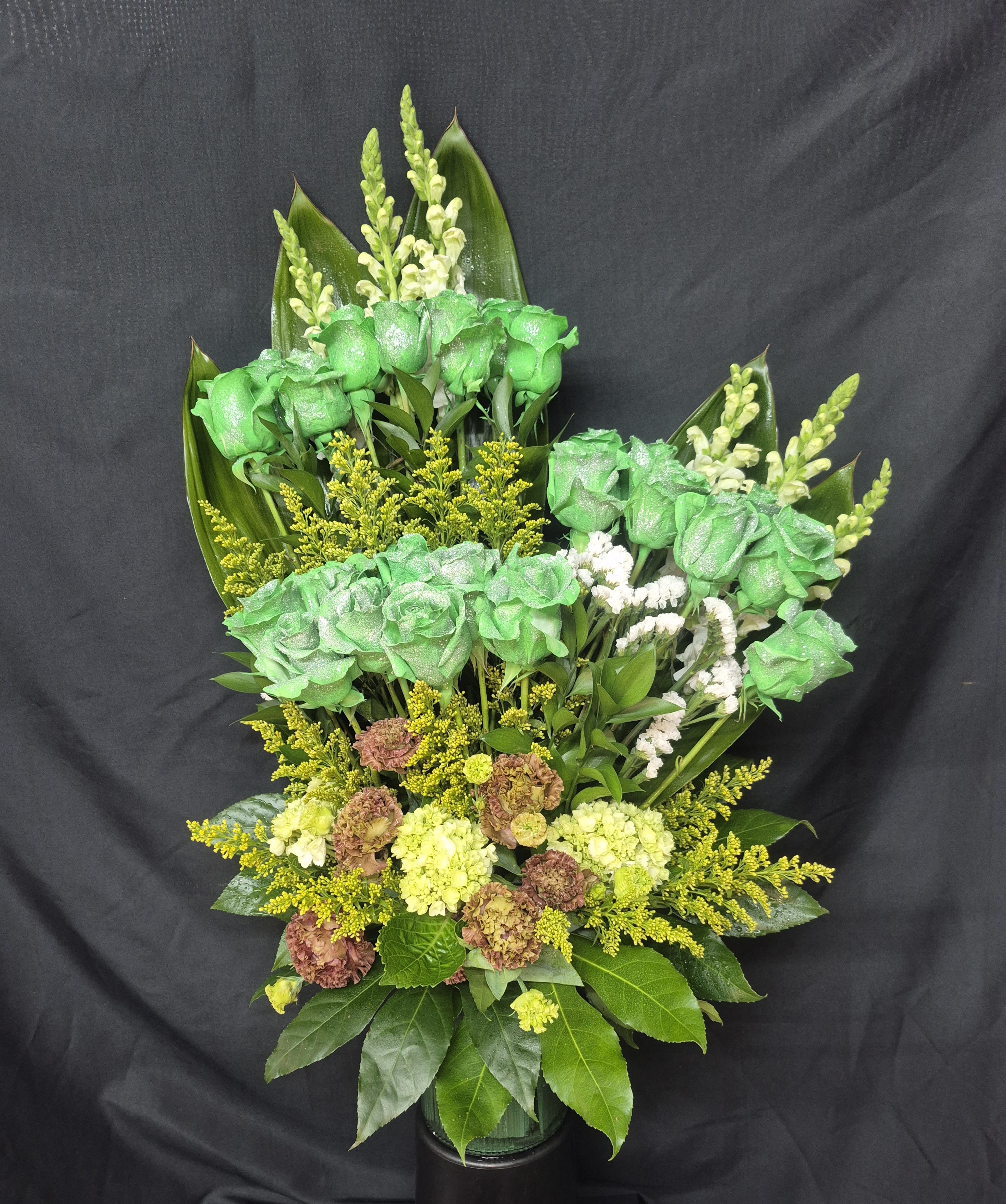 Green Charm Delight - A stunning one sided tall arrangement featuring 24 (plus) green long stemmed roses. Accompanied with white snap-dragons, solid asters, yellow hydrangeas and many more additions. Excellent for St. Patrick's day celebration,  birthday, or for someone who just loves green :) 