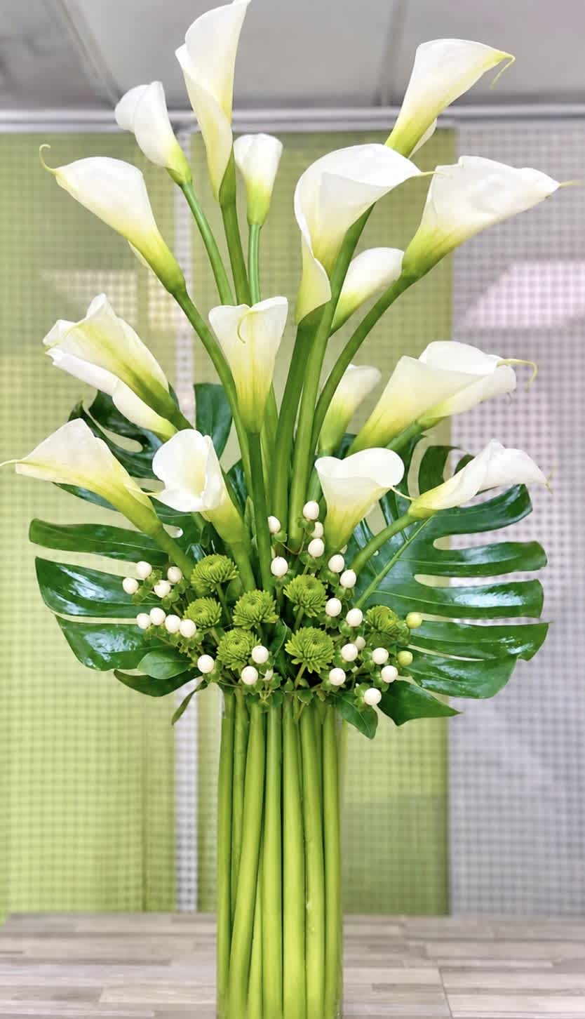 Bouquet of white calla lilies with green accents and tropical leaves