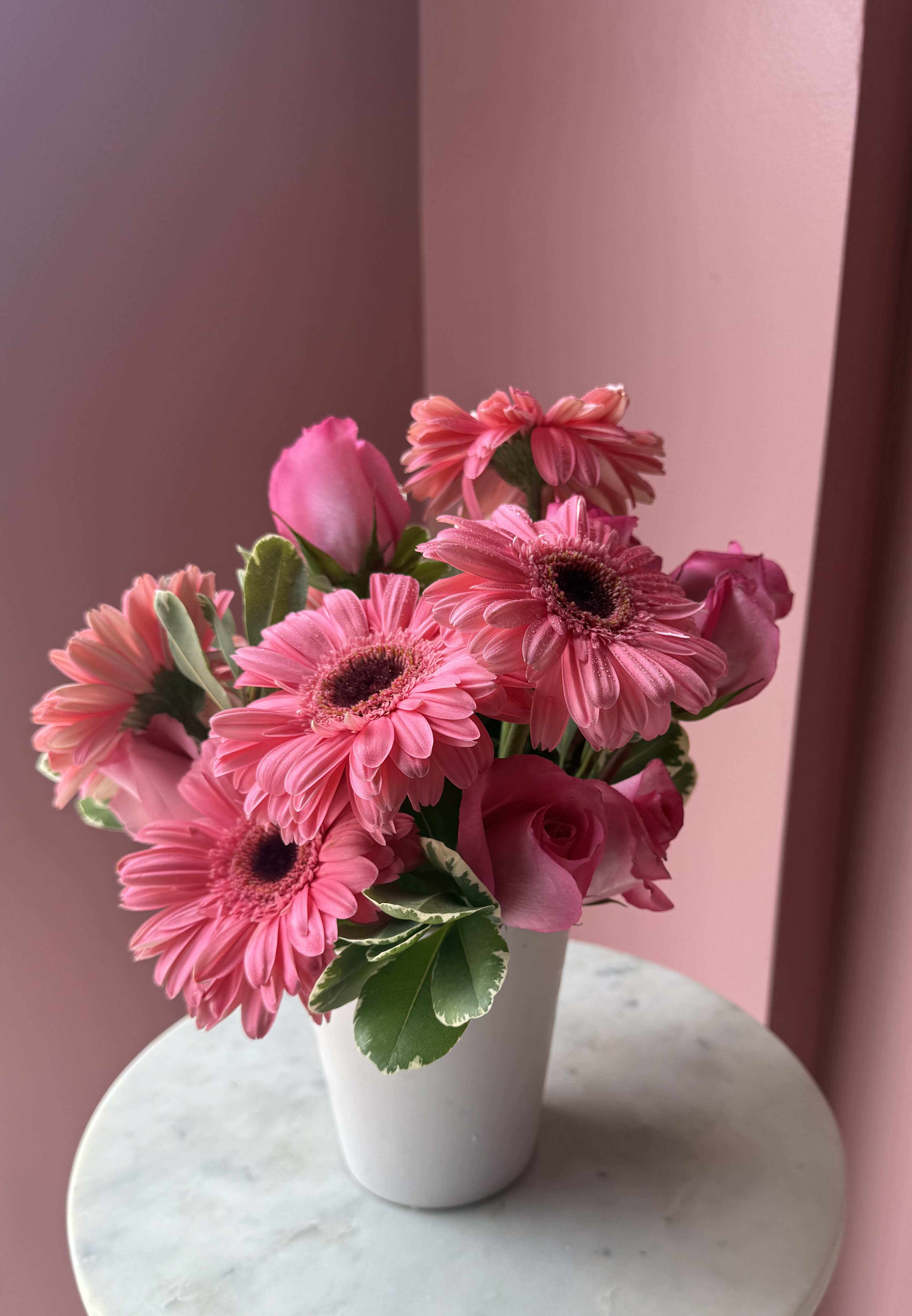 Pink gerbera daisies and roses in a white vase