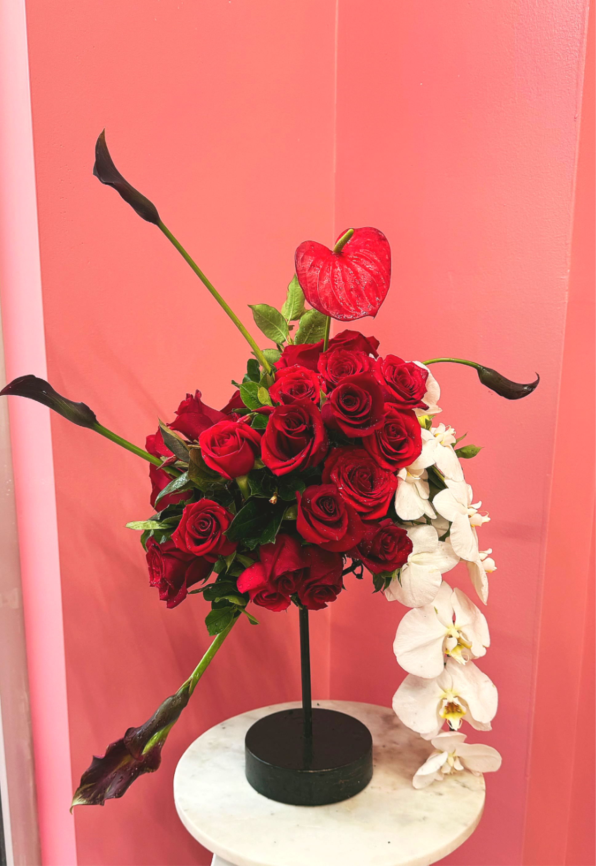 Red roses and white orchids arranged in a black vase