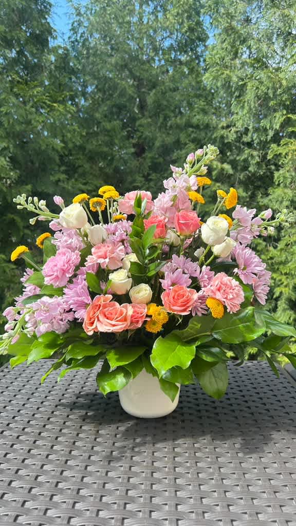 Mixed pink and white flowers in a white vase with yellow accents