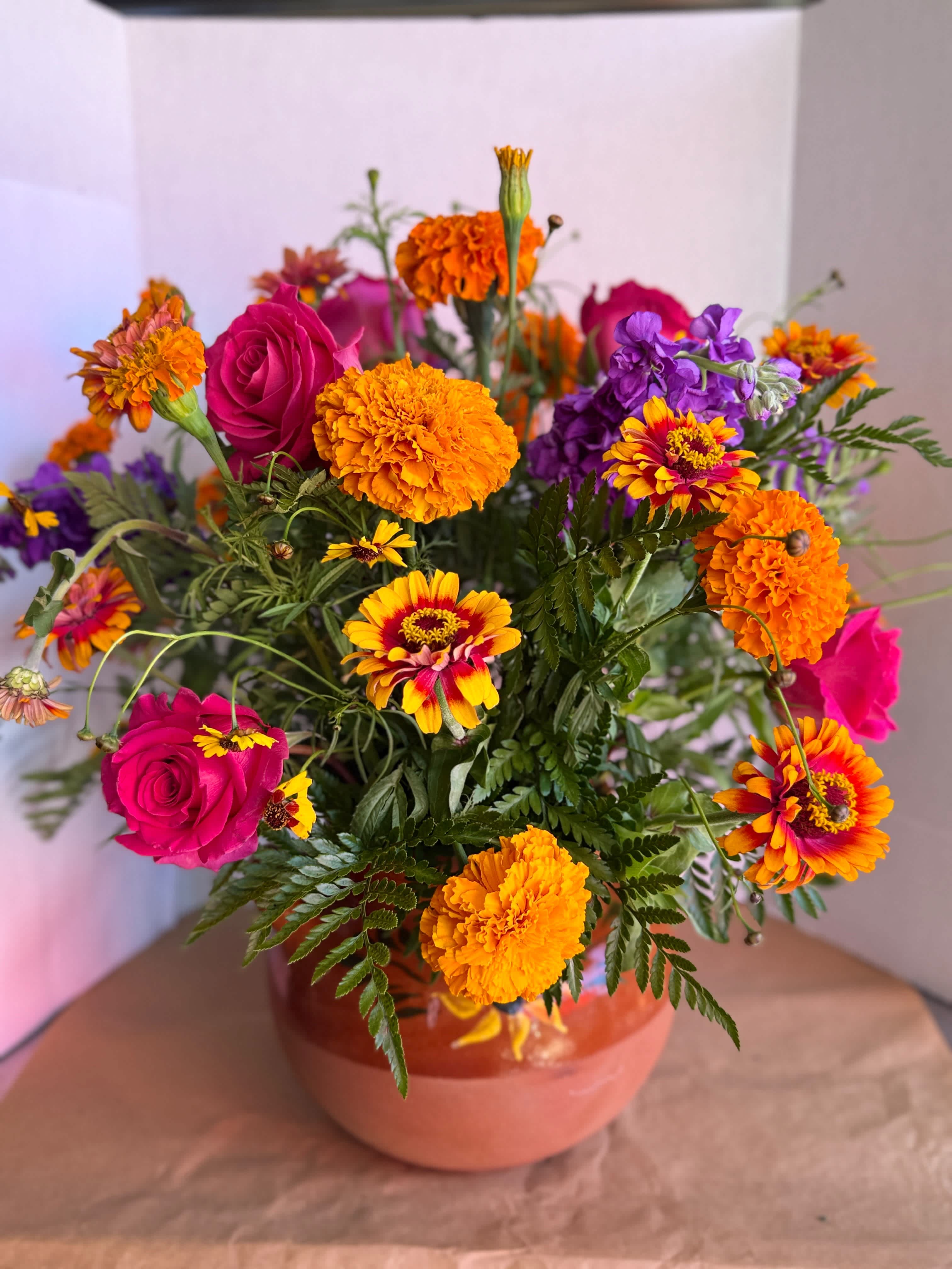 Bright mixed bouquet with pink roses and orange marigolds in a vase