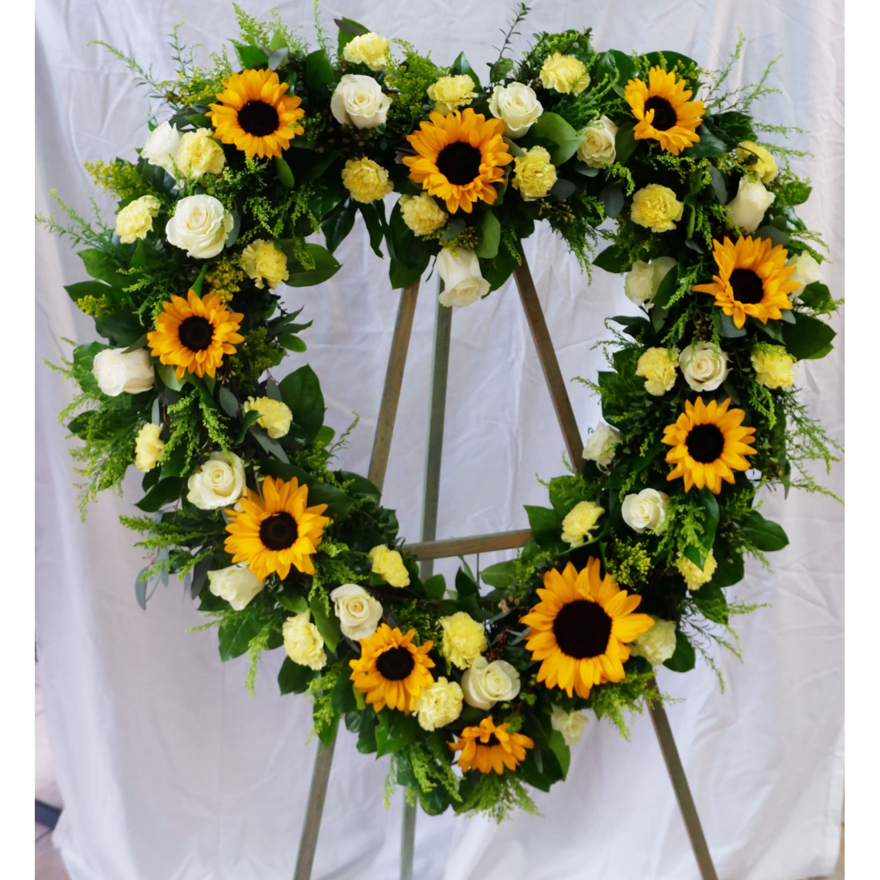 Heart-shaped floral wreath with sunflowers, white roses, and yellow carnations