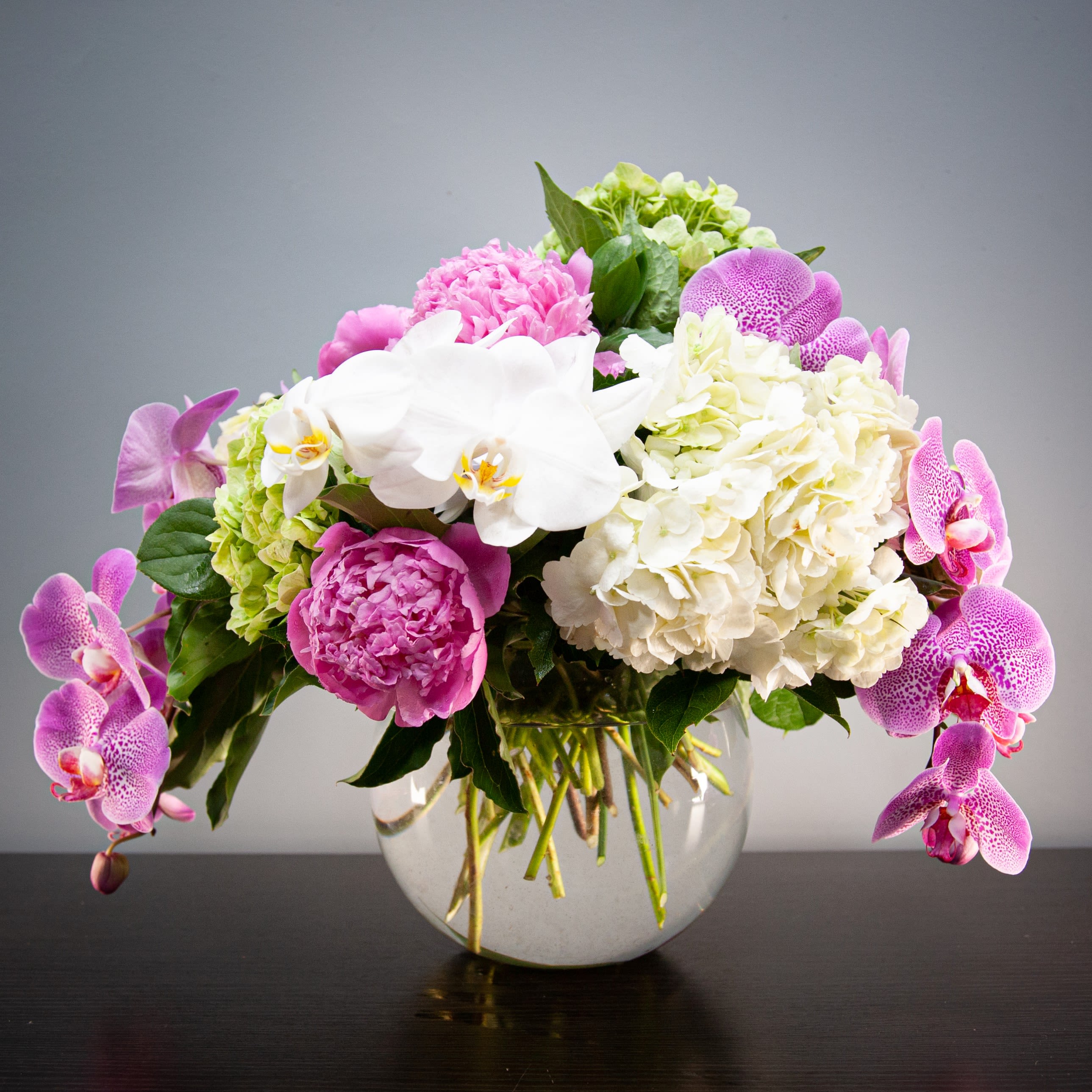 Luxe Peonies and Orchids (SF356) - This arrangement is filled with the finest high-end spring blooms. The branches of butterfly orchids create a beautiful cascading design.   Blooms in this arrangement: - White hydrangeas - Green hydrangeas - White butterfly orchids - Purple butterfly orchids - Peonies
