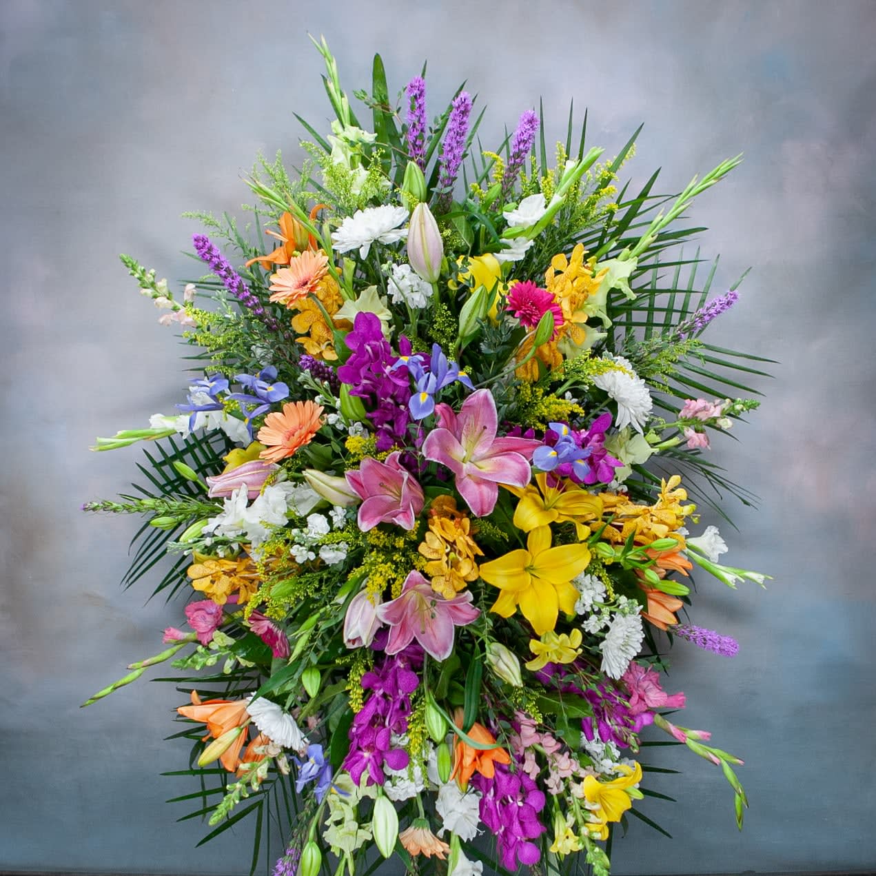 Large mixed floral spray with lilies, orchids, and daisies