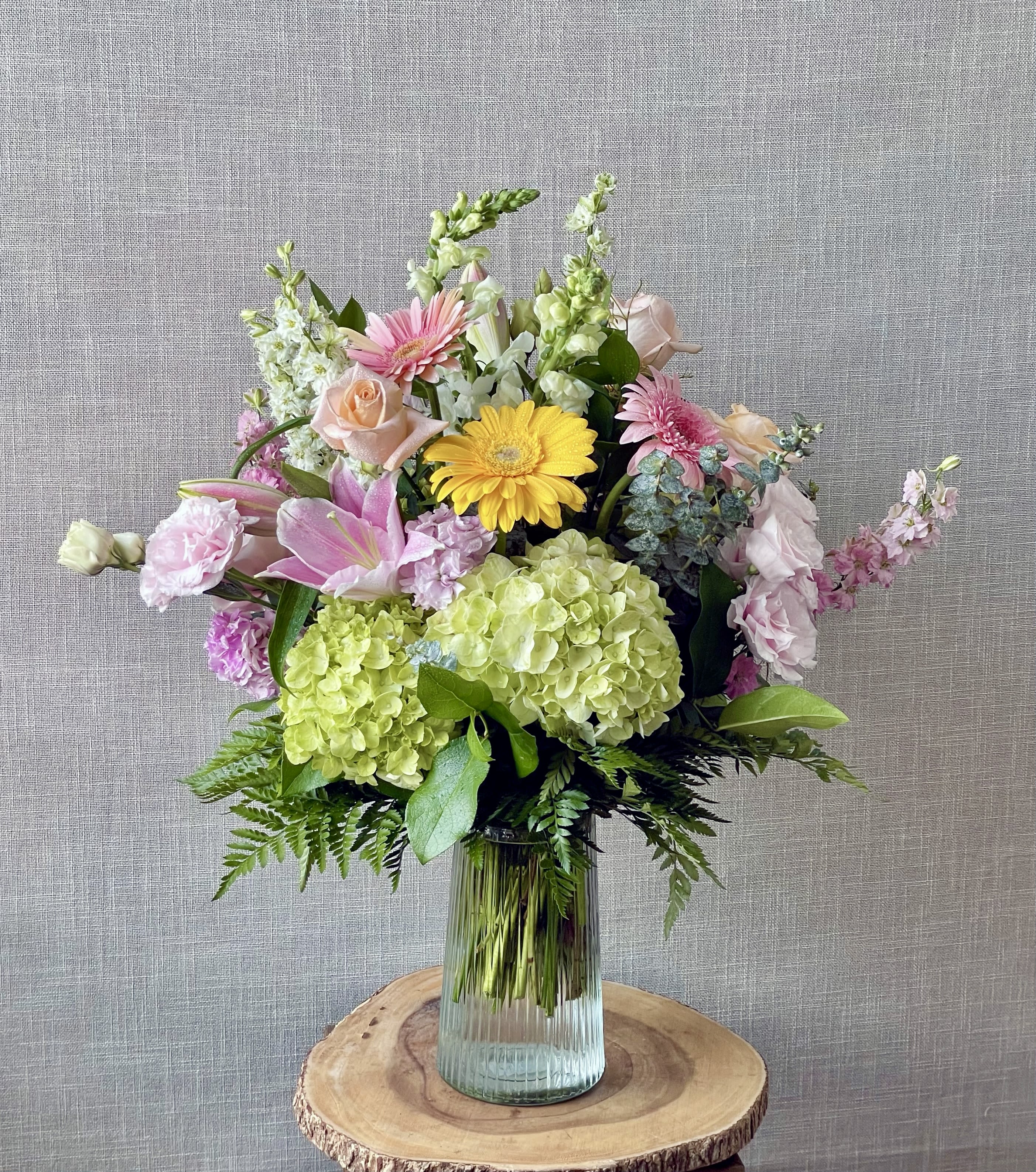 Mixed bouquet with pink, yellow, and green flowers in a glass vase