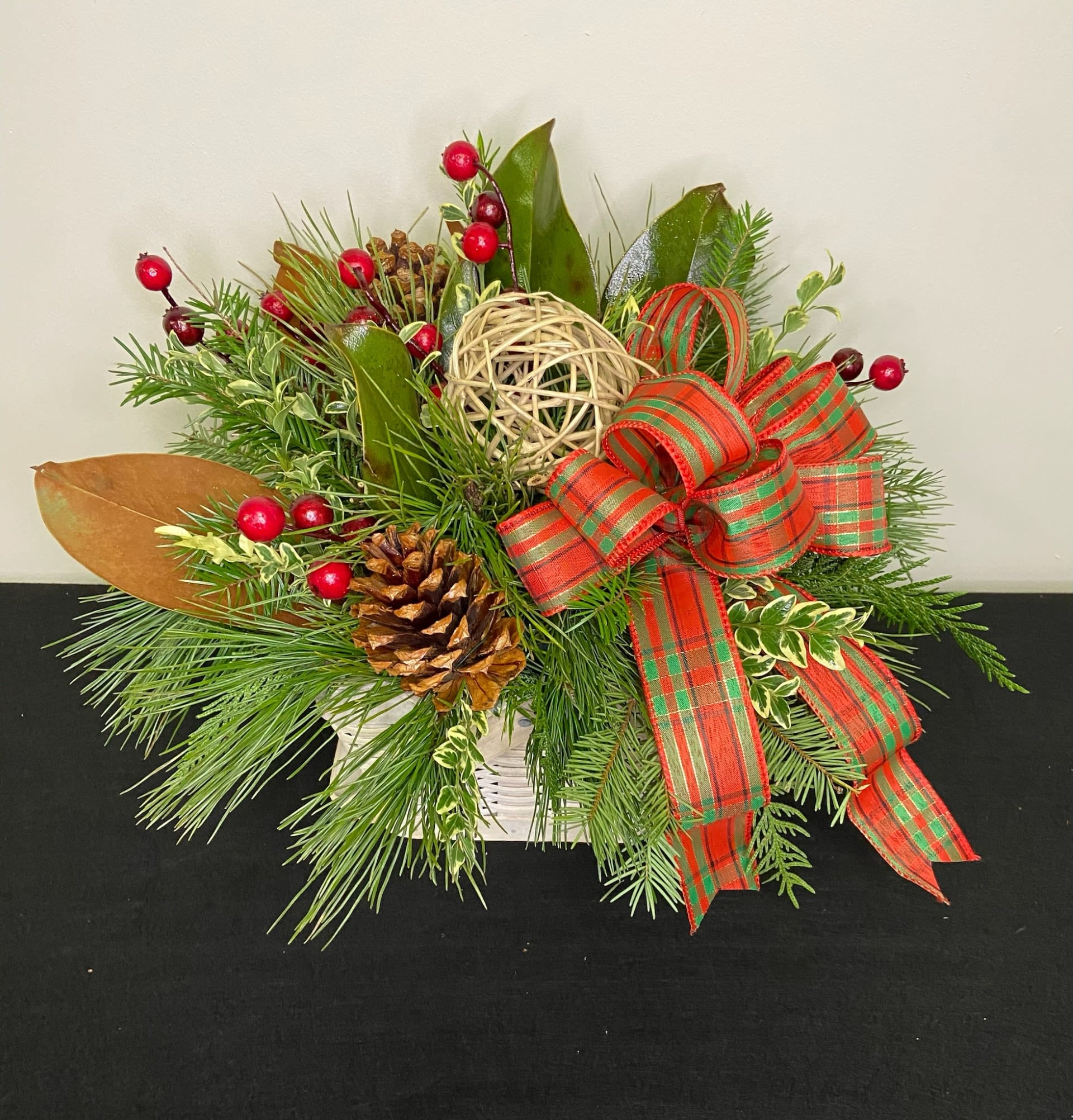 Cabin Coziness by Chasing Petals - Mixed wintergreens and pine cones accented with deep red berries and a bow, this cutie will last all winter long with regular watering to rehydrate the floral foam!   Bow colour is flexible, please call us to confirm any changes.