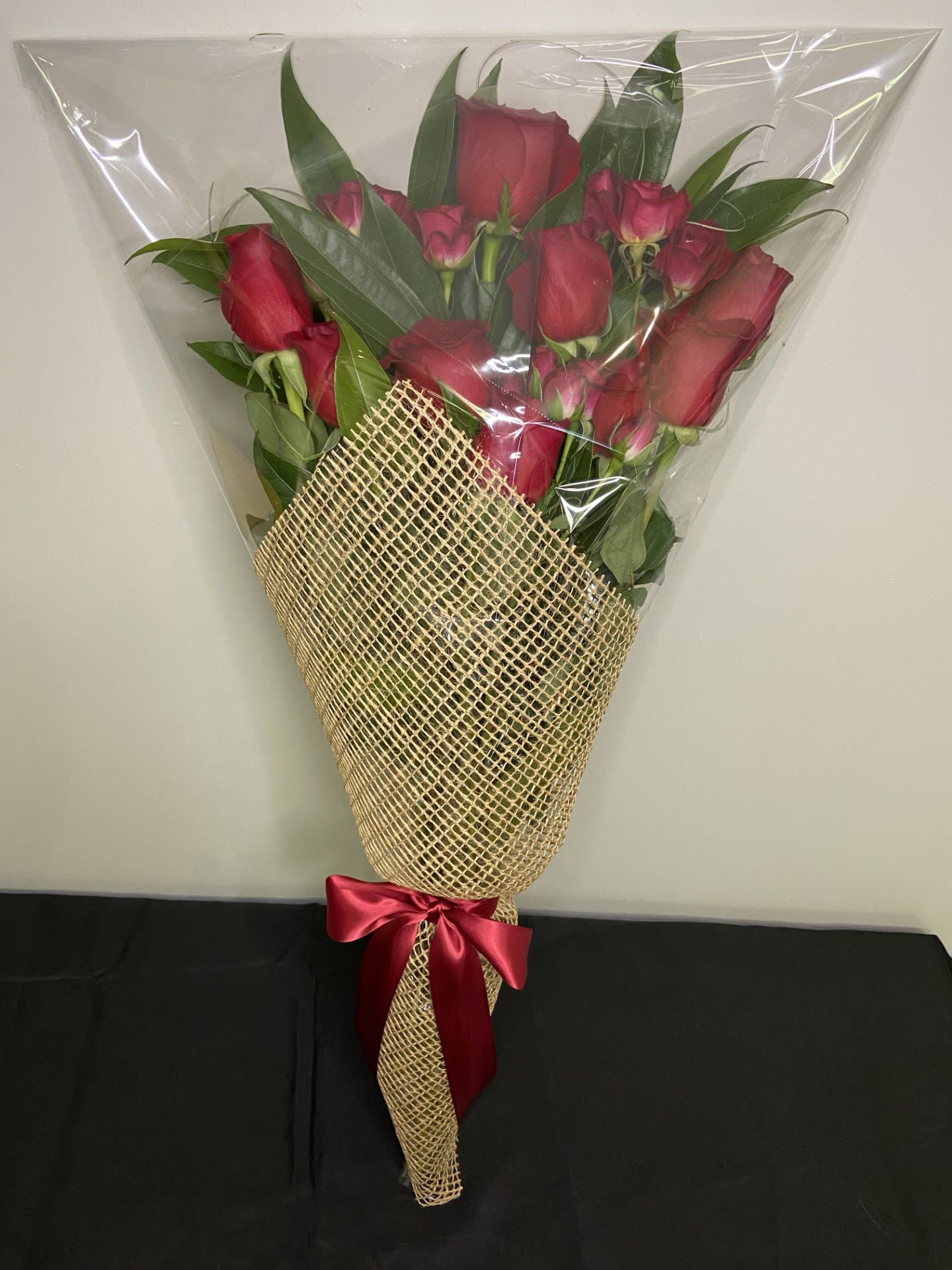 Bouquet of red roses wrapped in clear plastic and burlap with a red ribbon