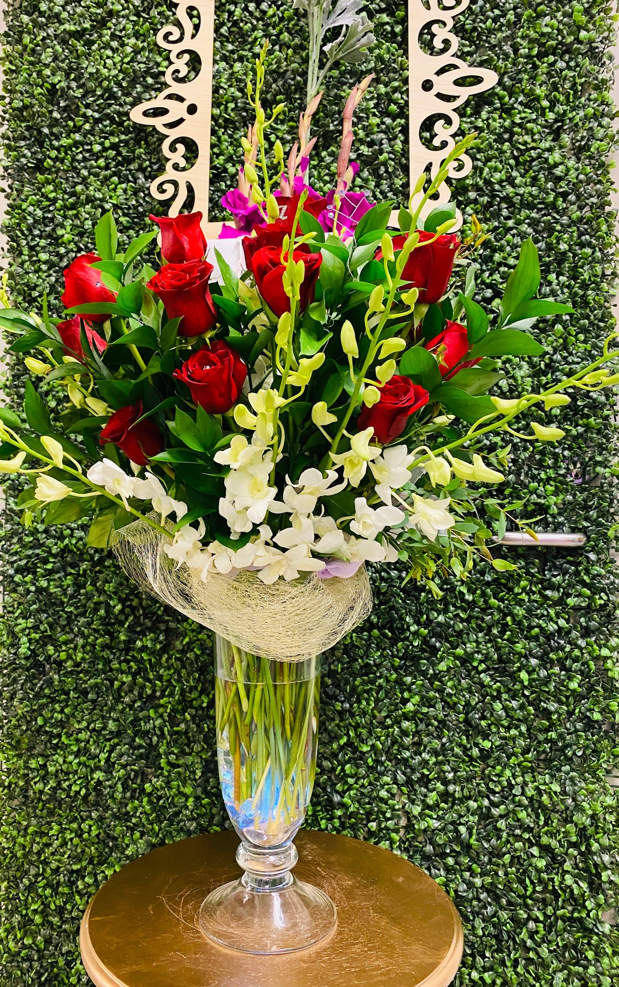 Tall bouquet of red roses and white orchids in a clear glass vase