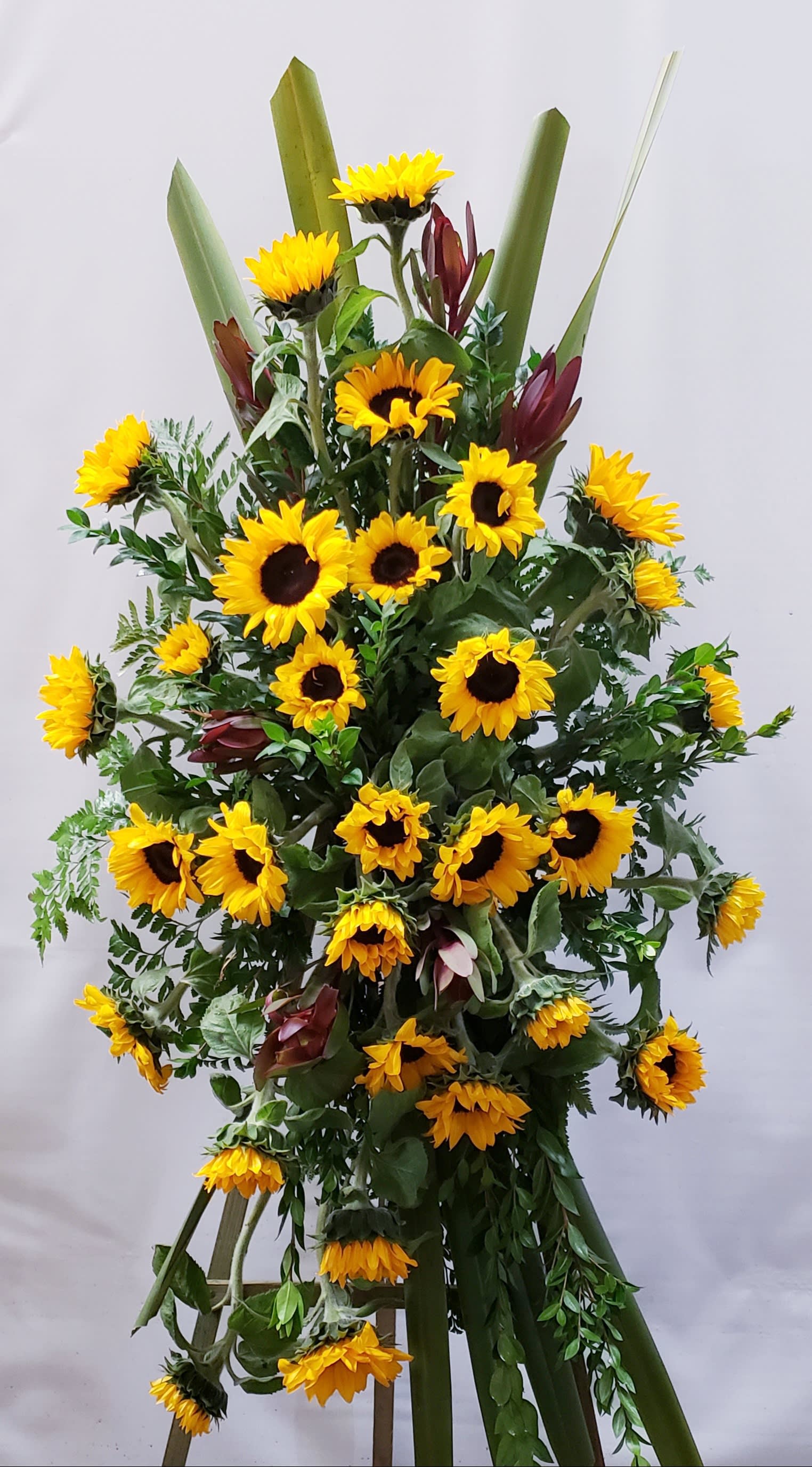 Tall sunflower arrangement with burgundy accents and greenery