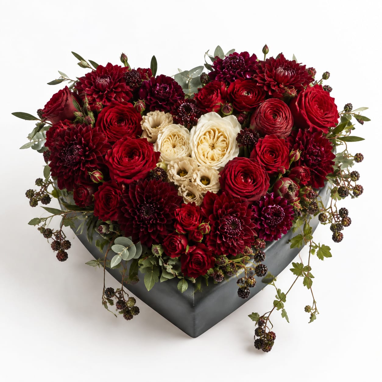 Heart-shaped arrangement of red and cream flowers in a dark box